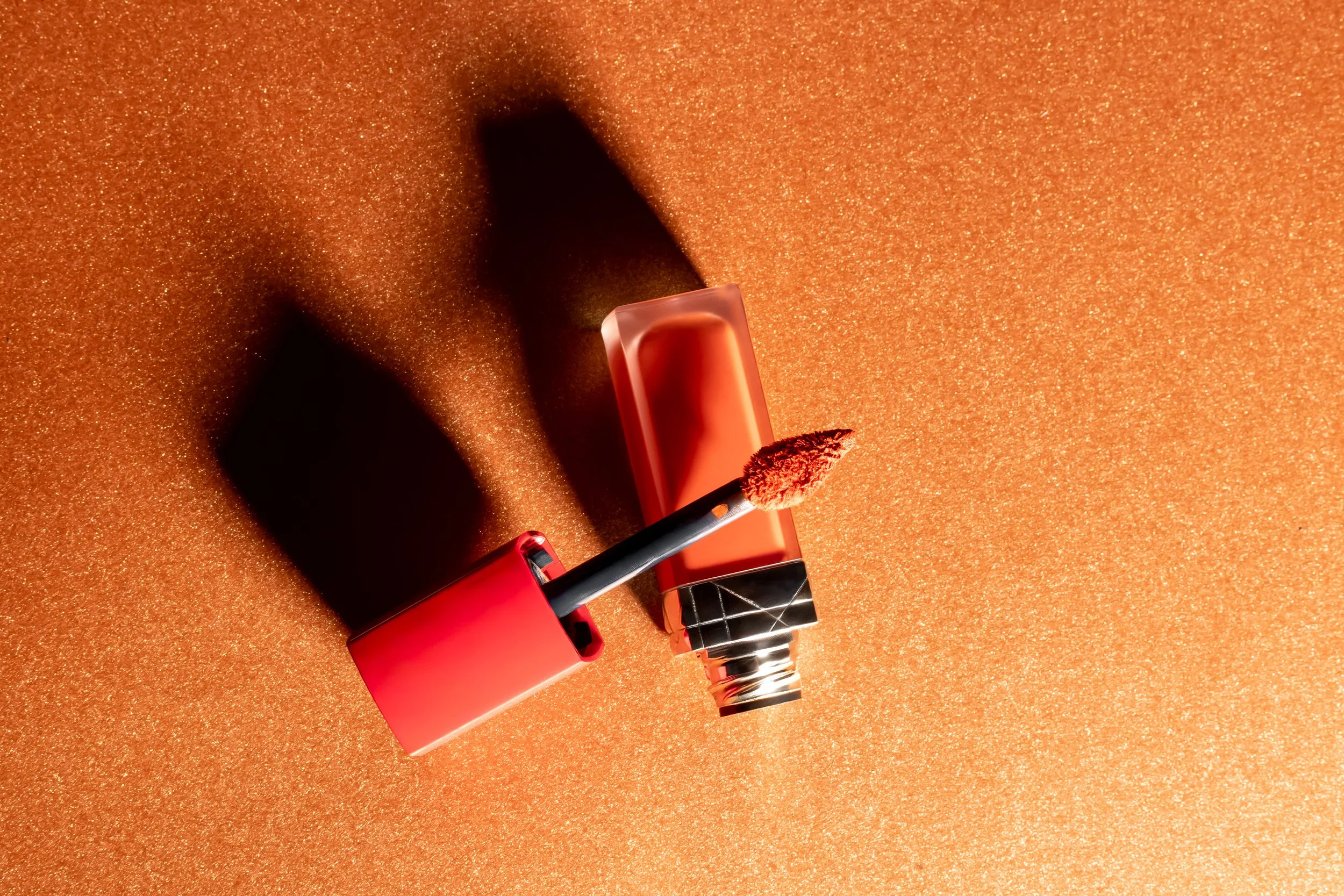 Conseil de rouge à lèvres ouvert avec applicateur sur une surface orange brillante.