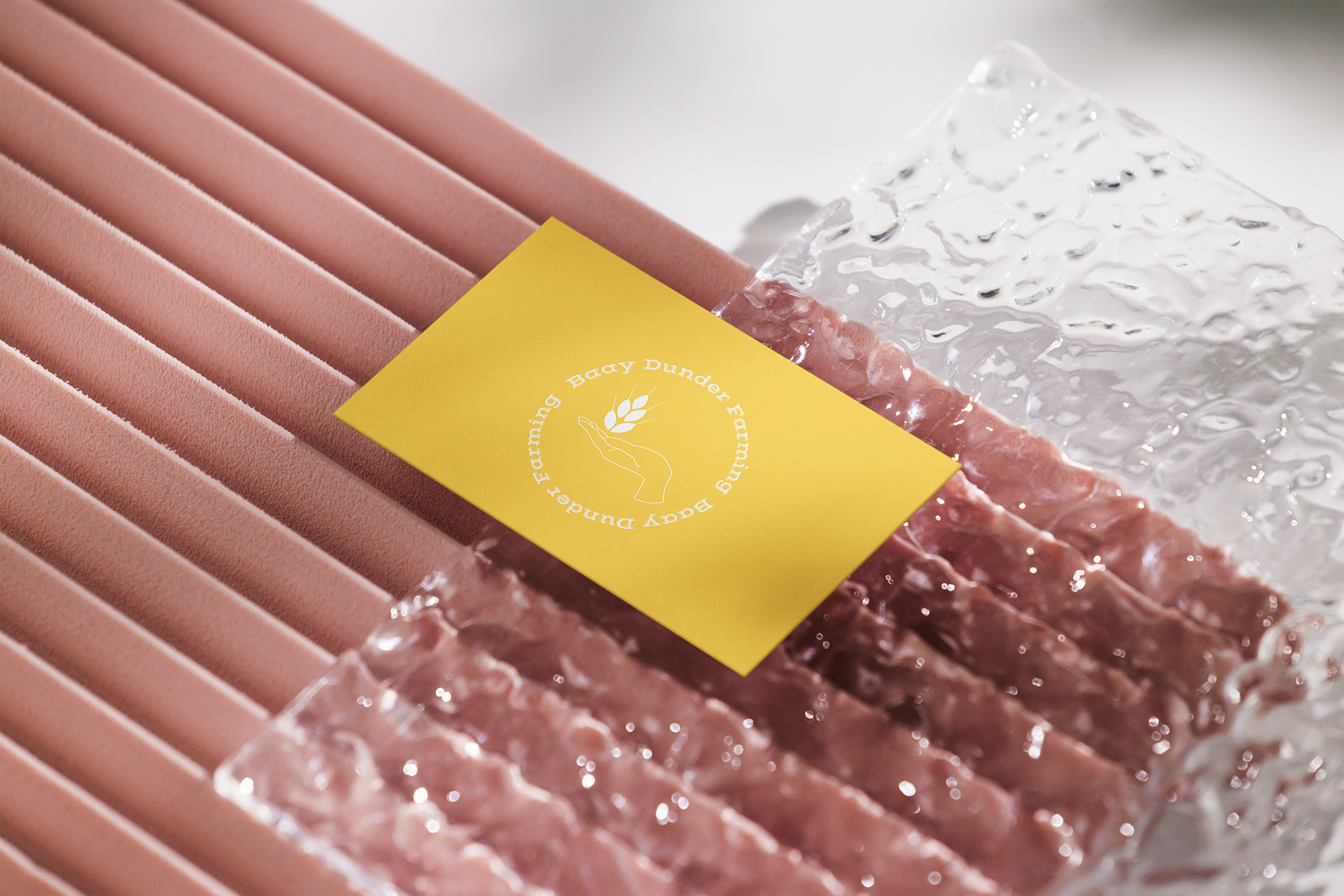 Photo d'un massage avec des pierres chaudes, une serviette rose et une carte de visite jaune avec le logo 'Bauy Dunder Farming'.