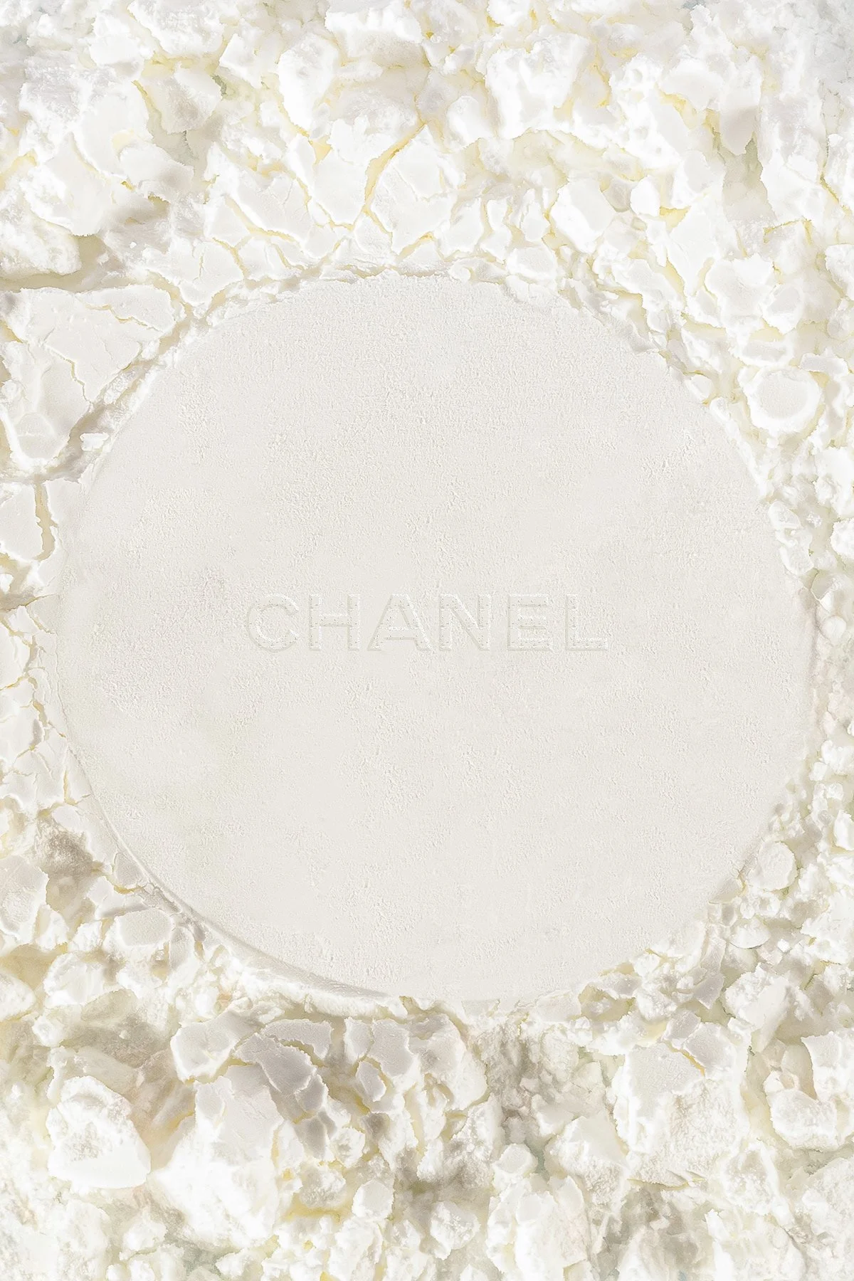 Une boîte blanche de parfum Chanel entourée de morceaux de cire ou de résine blanc.