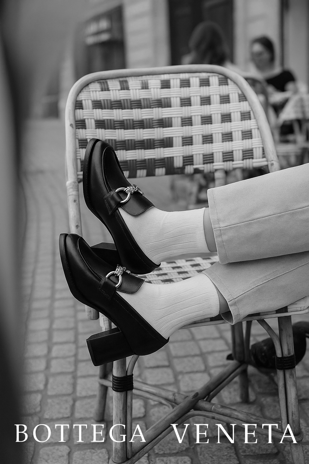 Chaussures à talons noires, vêtements et chaussures de style homme, personne assise avec jambes croisées, enseigne Bottega Veneta.