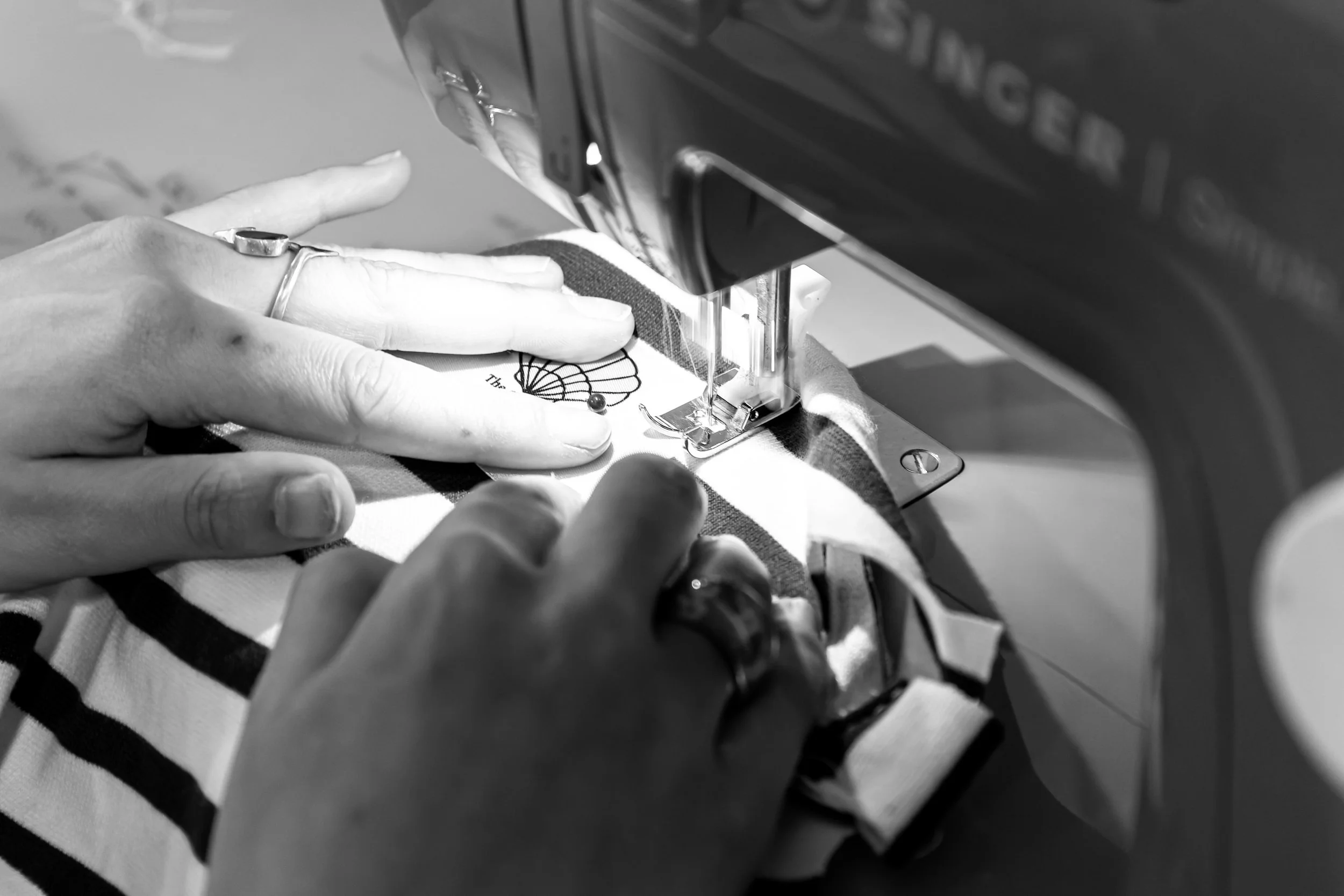 Personne utilisant une machine à coudre pour fabriquer un vêtement avec un tissu à rayures.