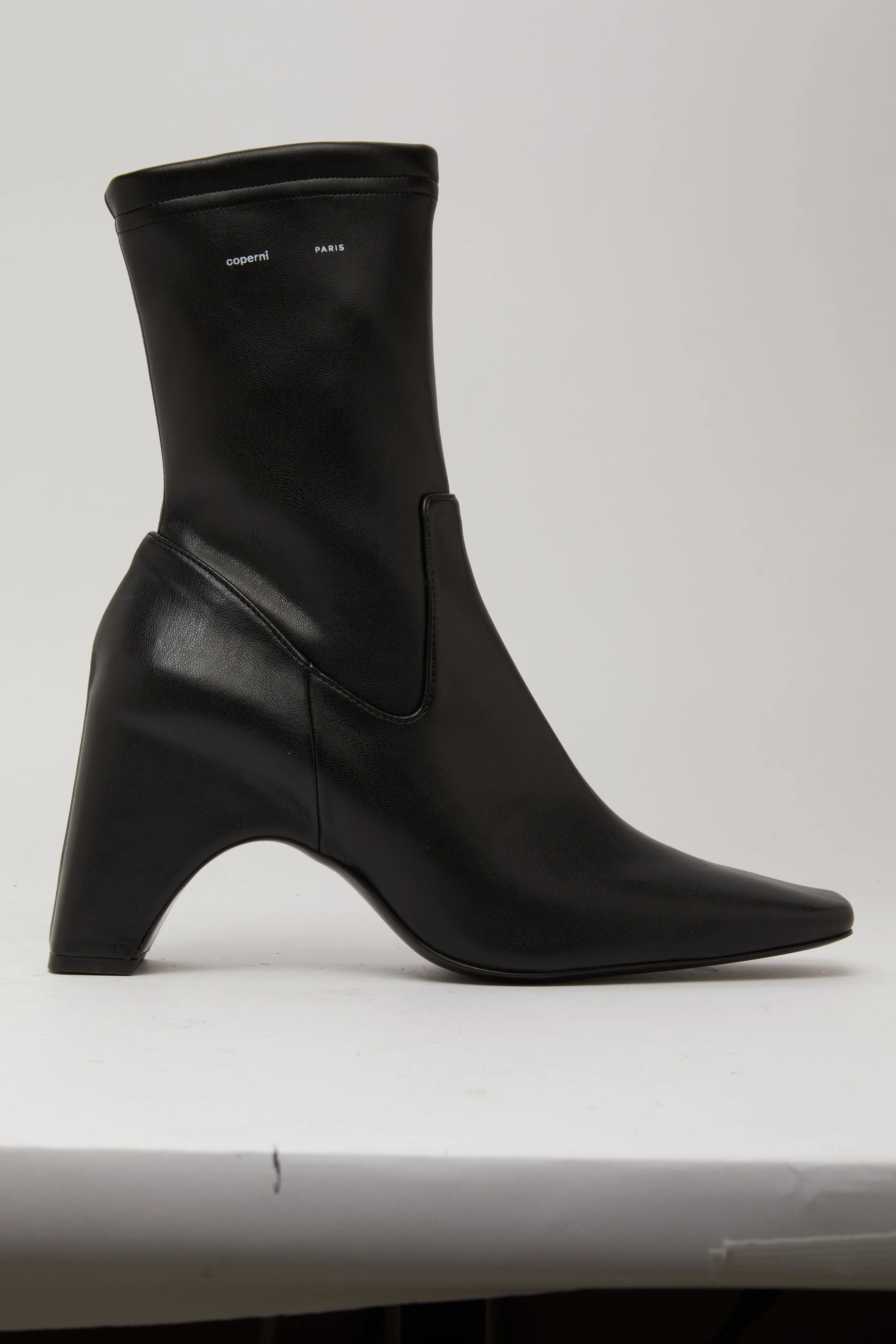 Botte noire en cuir avec un talon épais et pointu, marqué avec le texte 'coperni PARIS'.