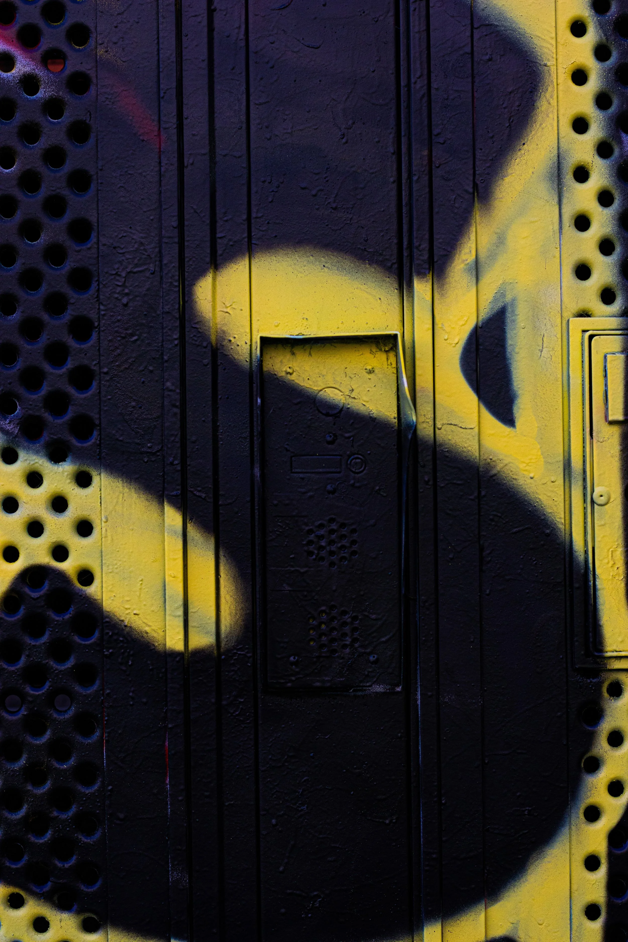 Graffiti de couleur noire et jaune sur une surface métallique urbaine.