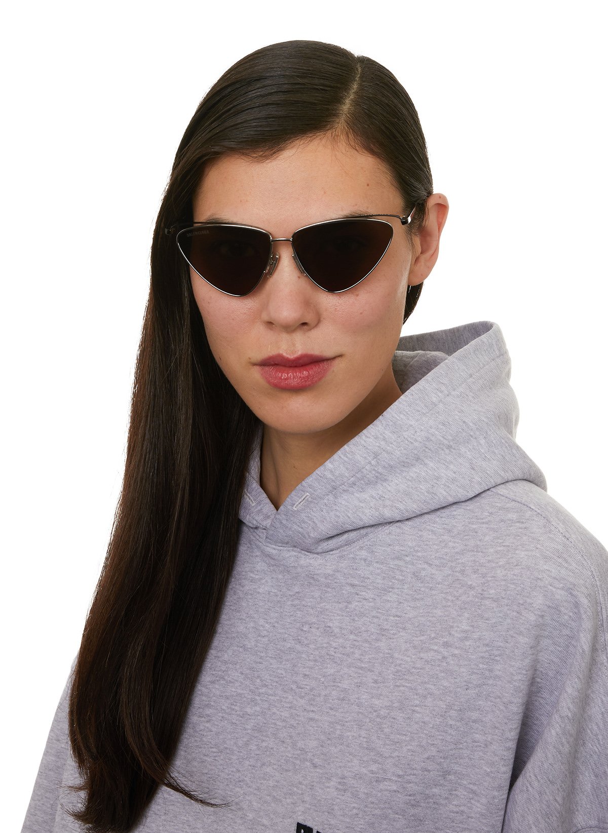 Une femme portant des lunettes de soleil noires et un sweat à capuche gris clair.
