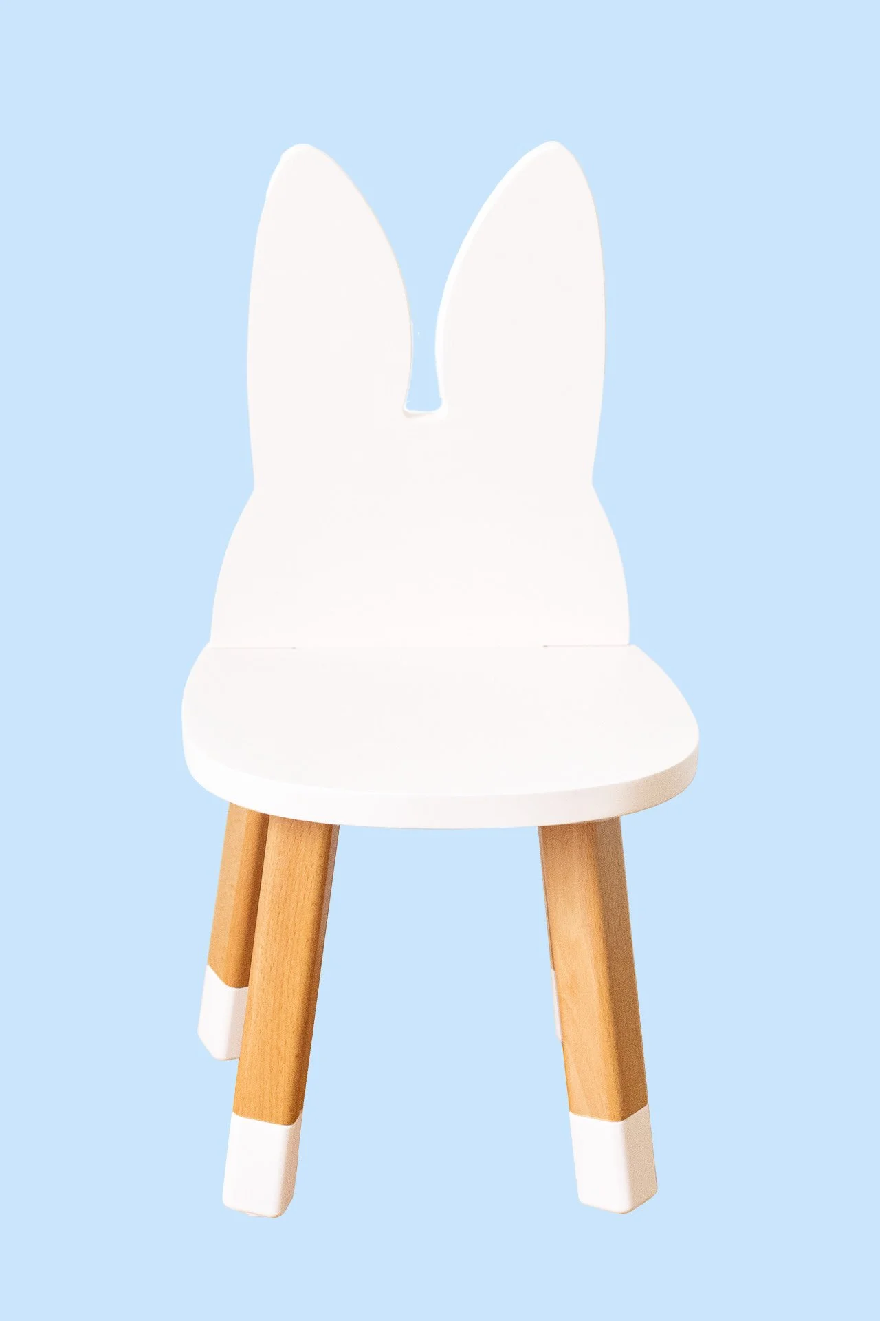 Chaises pour enfants avec un design de lapin, assise blanche, pattes en bois avec des bouts blancs, sur fond bleu clair.