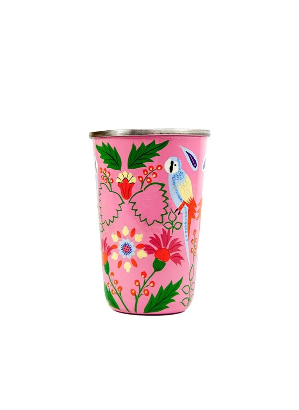 Une tasse en métal avec un design coloré de fleurs, de feuilles et un toucan sur fond rose.