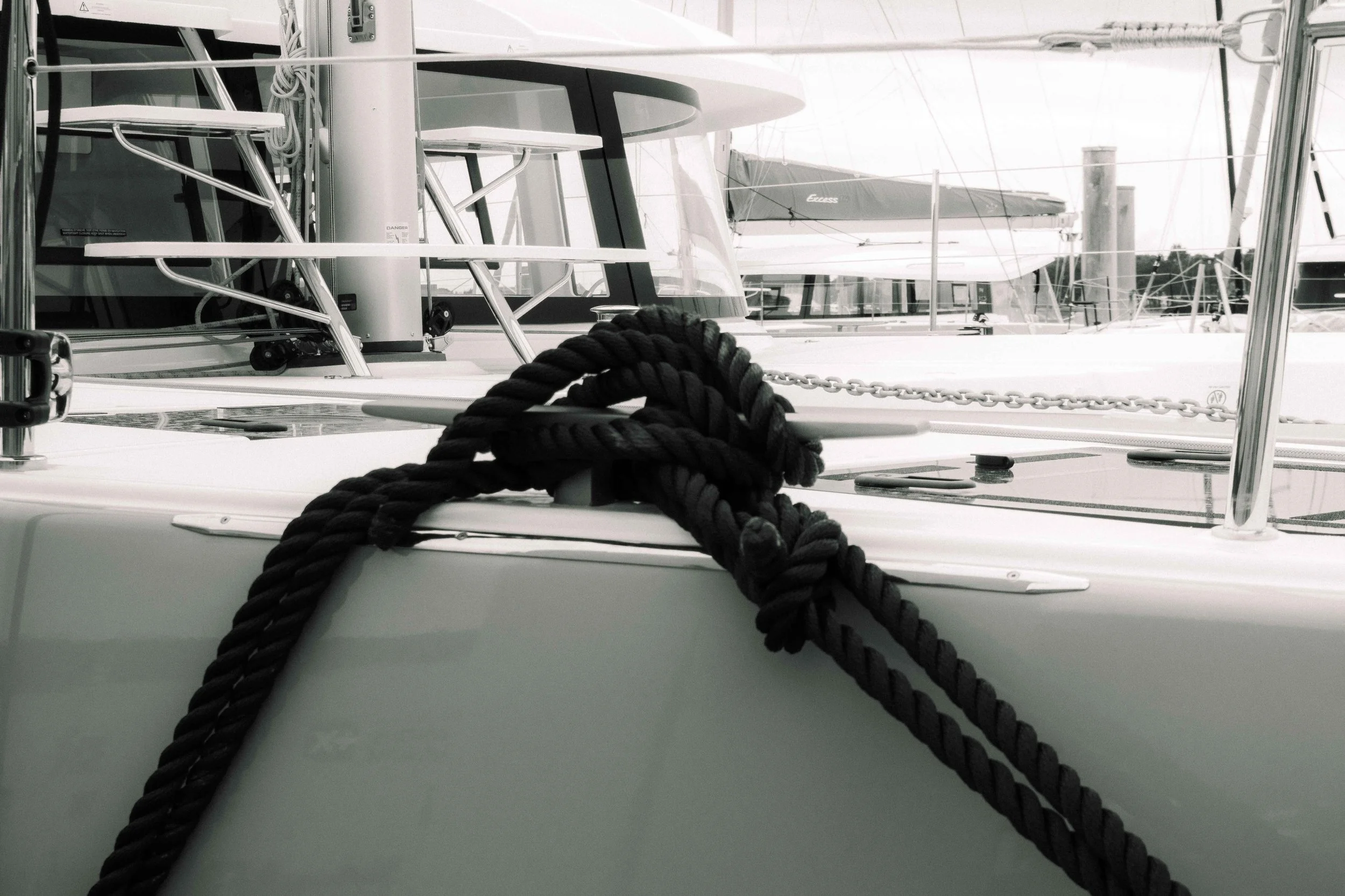Rope attached to the bow of a yacht at a marina with other boats in the background.