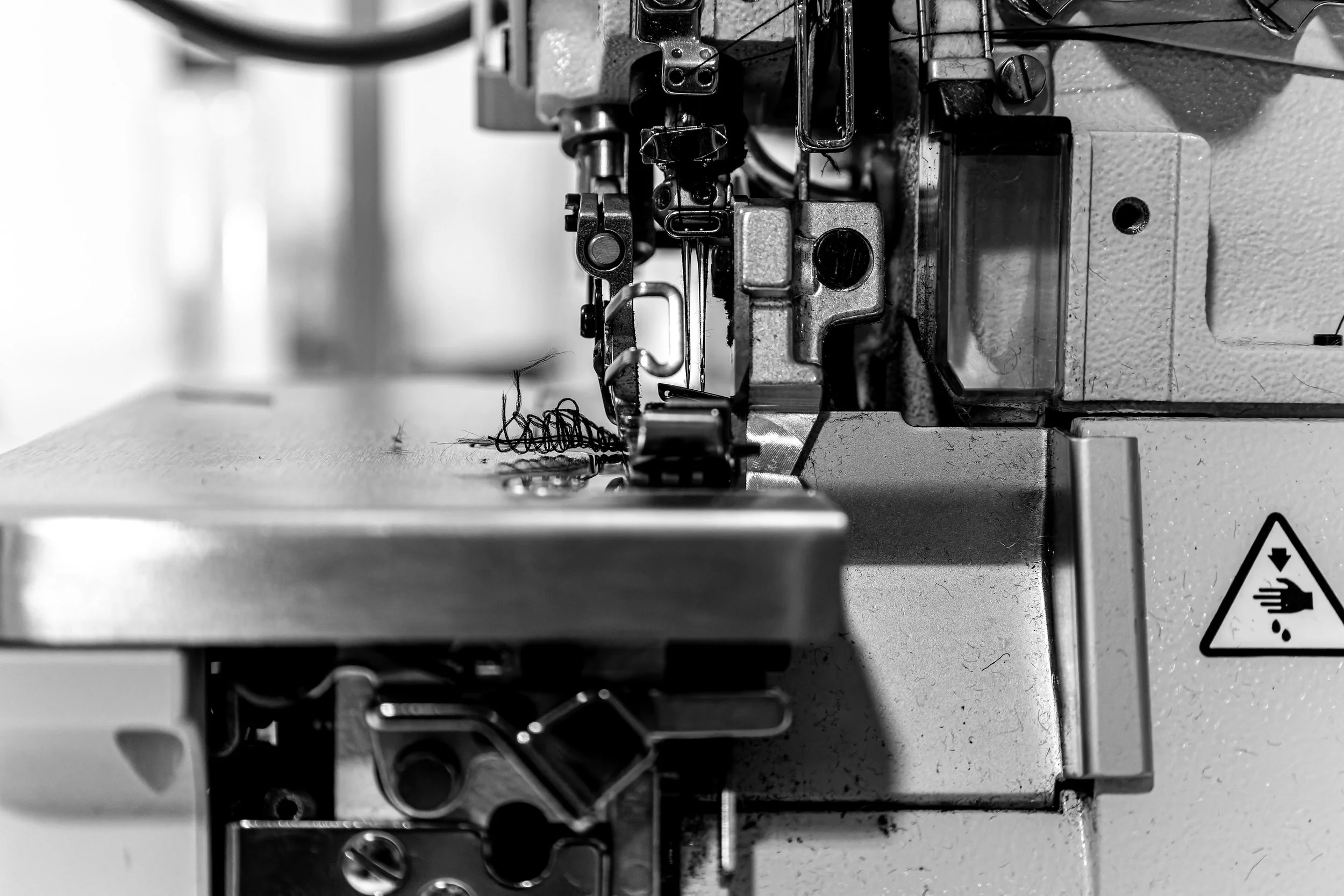 Une machine à coudre industrielle en métal, vue en gros plan en noir et blanc.