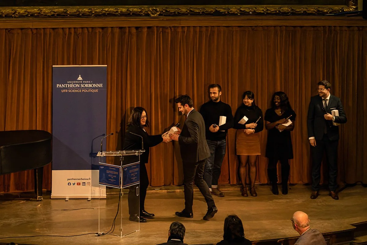 Une cérémonie d'attribution de prix à l'Université Paris 1 Panthéon-Sorbonne, avec des personnes sur scène recevant une distinction.