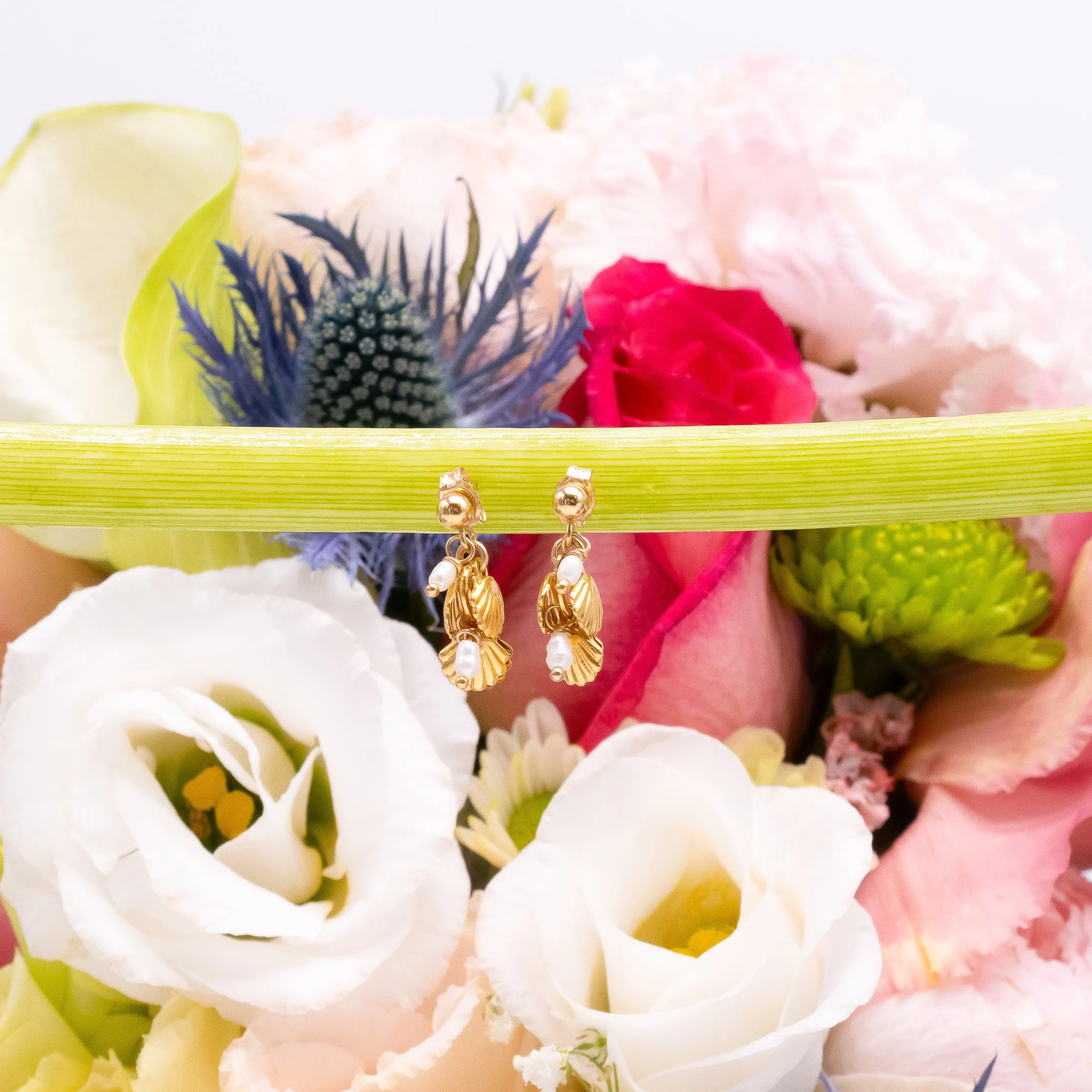 Bouquet de fleurs avec des boucles d'oreilles en or suspendues au centre.