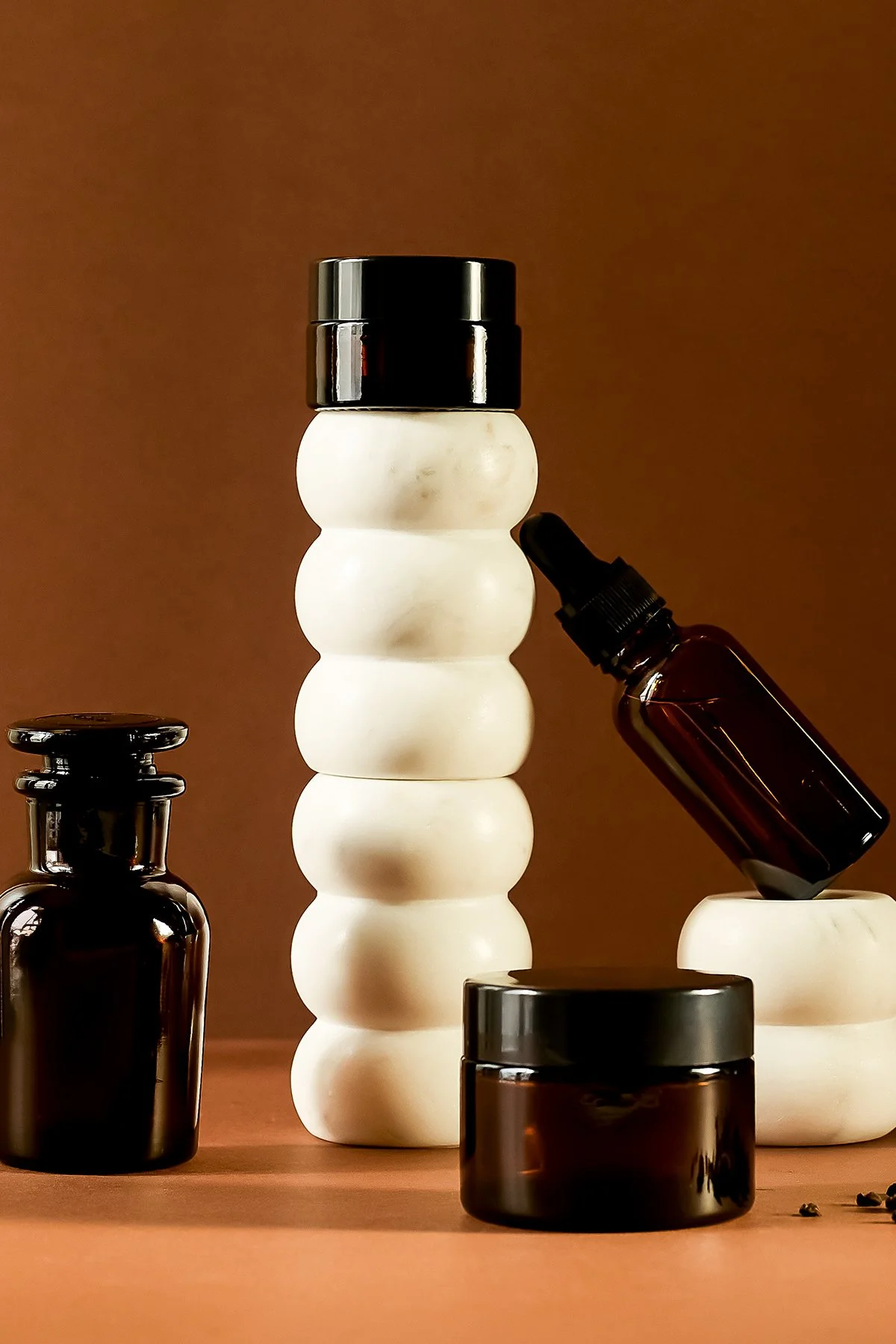 Différents flacons en verre et en céramique de produits de beauté ou soins, avec un fond beige clair et une disposition esthétique.