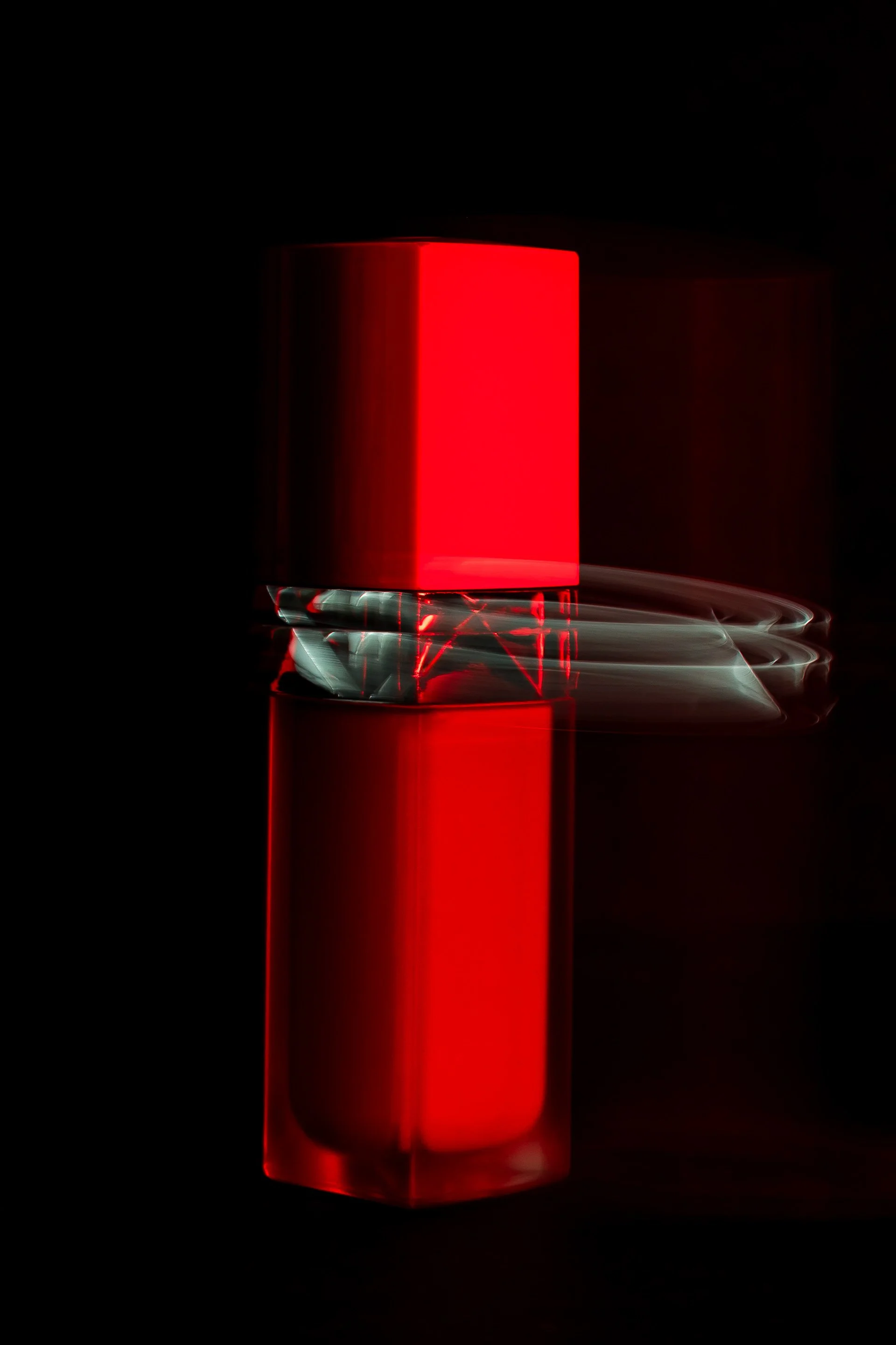 Une lampe ou un objet lumineux rouge avec des effets de lumière blanche en mouvement, reflété sur une surface sombre.