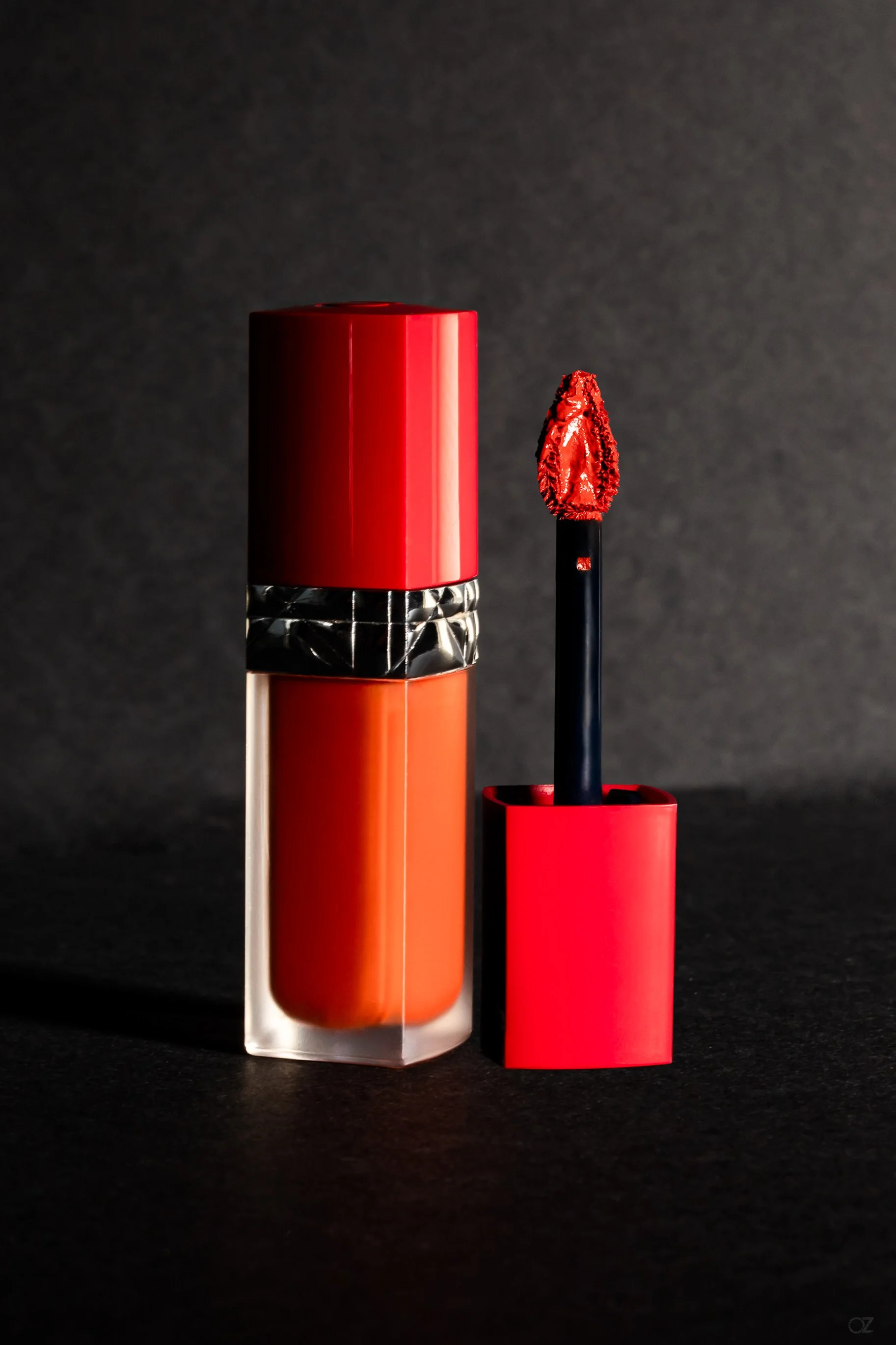 Vernis à lèvres rouge et orange avec son applicateur, sur fond noir