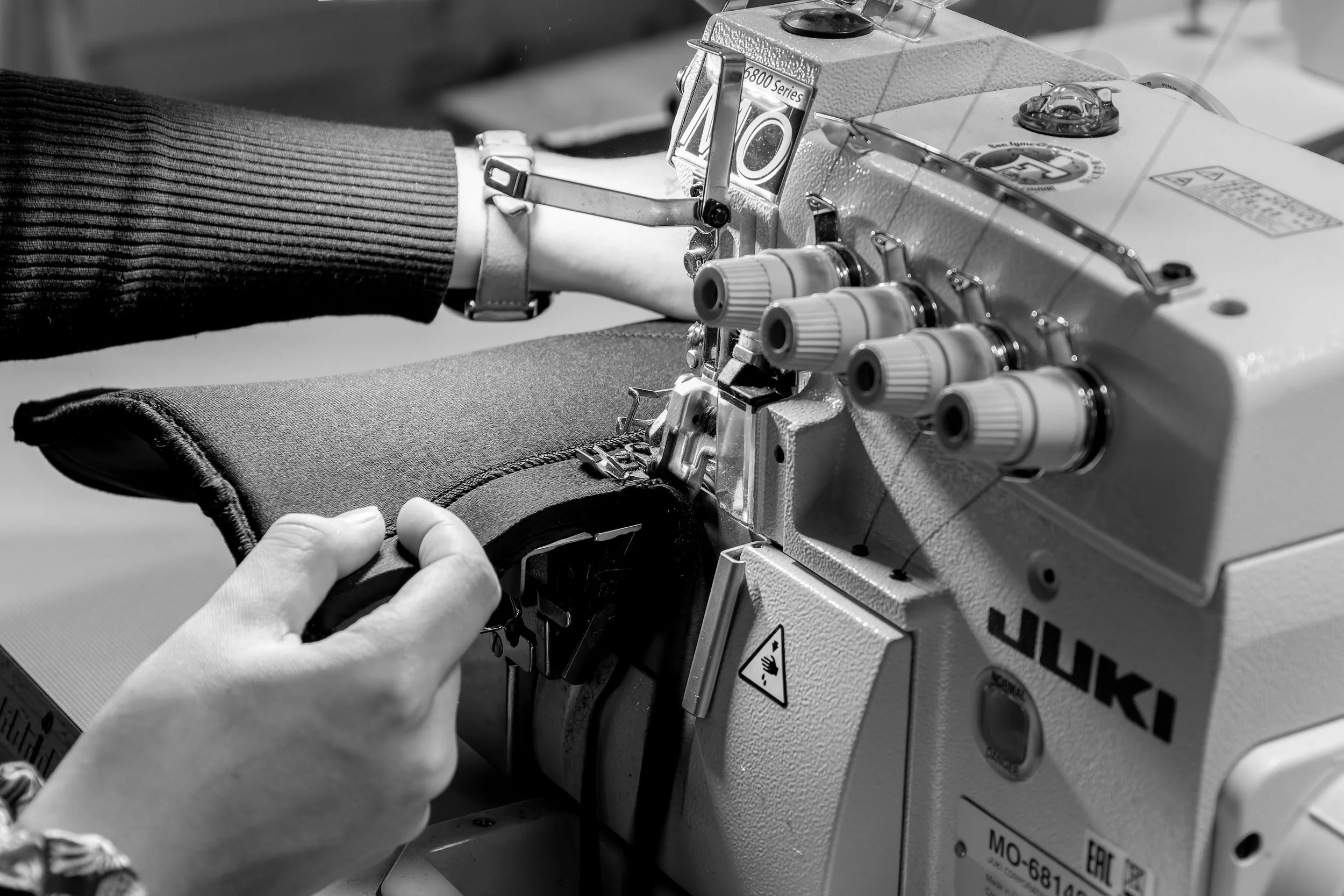 Travailleuse utilisant une machine à coudre industrielle pour fabriquer un vêtement ou un accessoire.