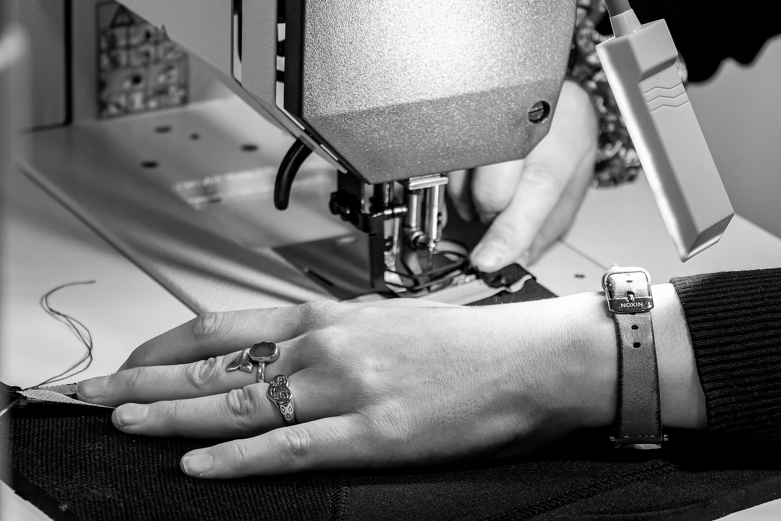 Une personne enregistre une broderie sur une machine à broderie assistée par ordinateur, en utilisant ses mains pour guider le tissu.