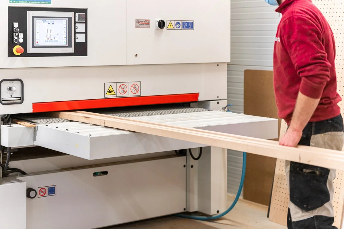 Une personne se tenant à côté d'une machine à découper du bois dans un atelier de menuiserie.