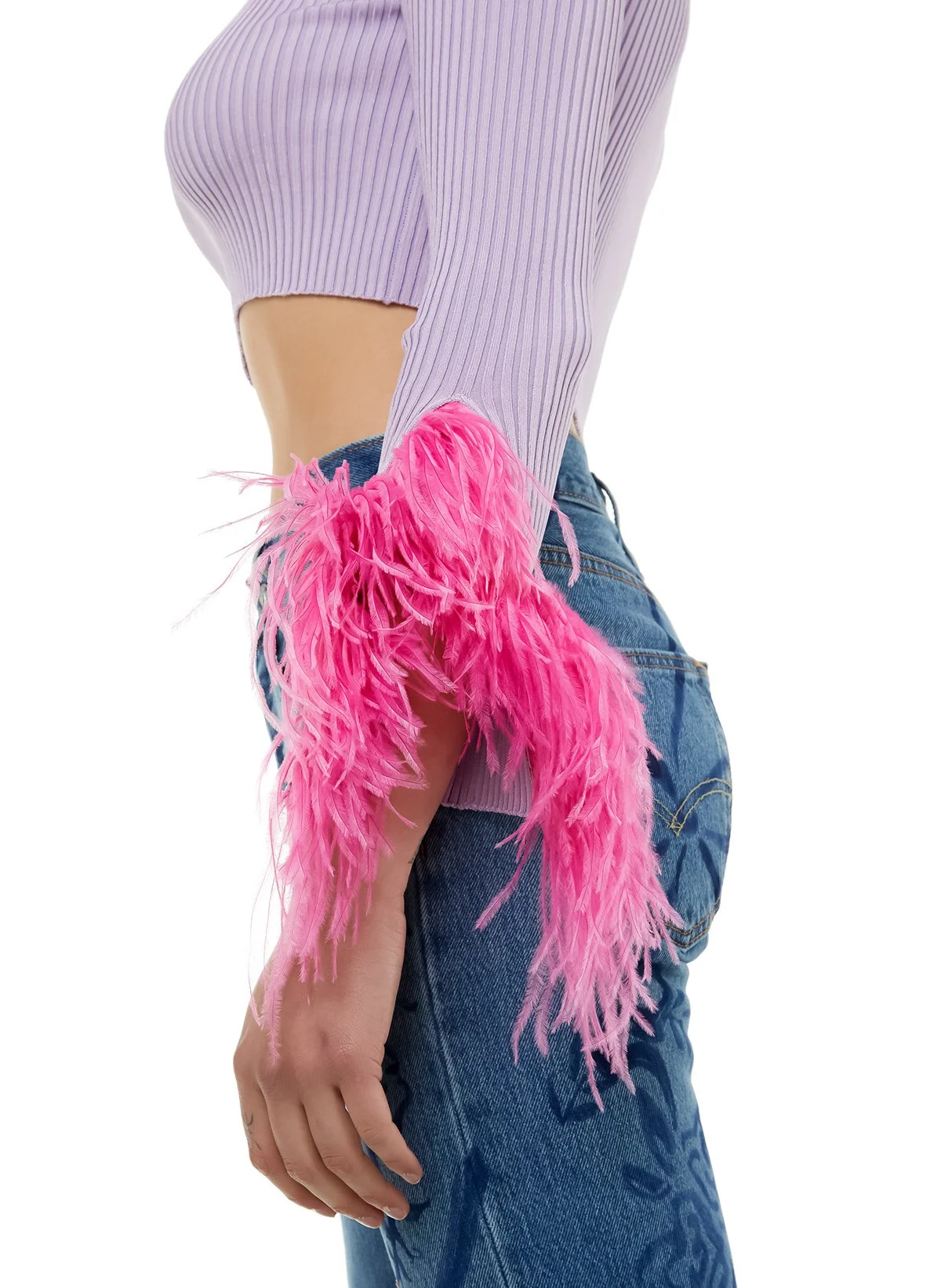 Une personne portant une pièce de vêtement avec de longues plumes roses, un haut violet rayé et un jean bleu.
