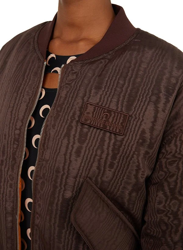 Veste en cuir marron avec une étiquette et une fermeture éclair, portée par une personne