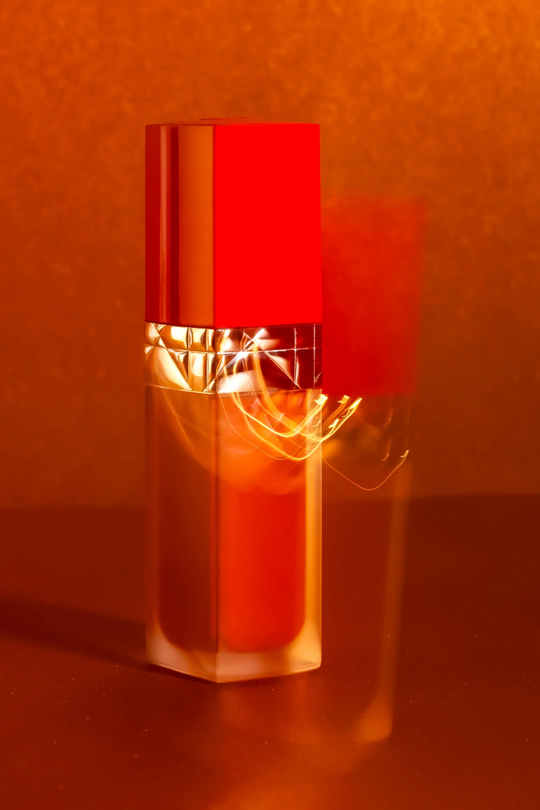 Flacon de parfum rouge et or sur fond rouge.