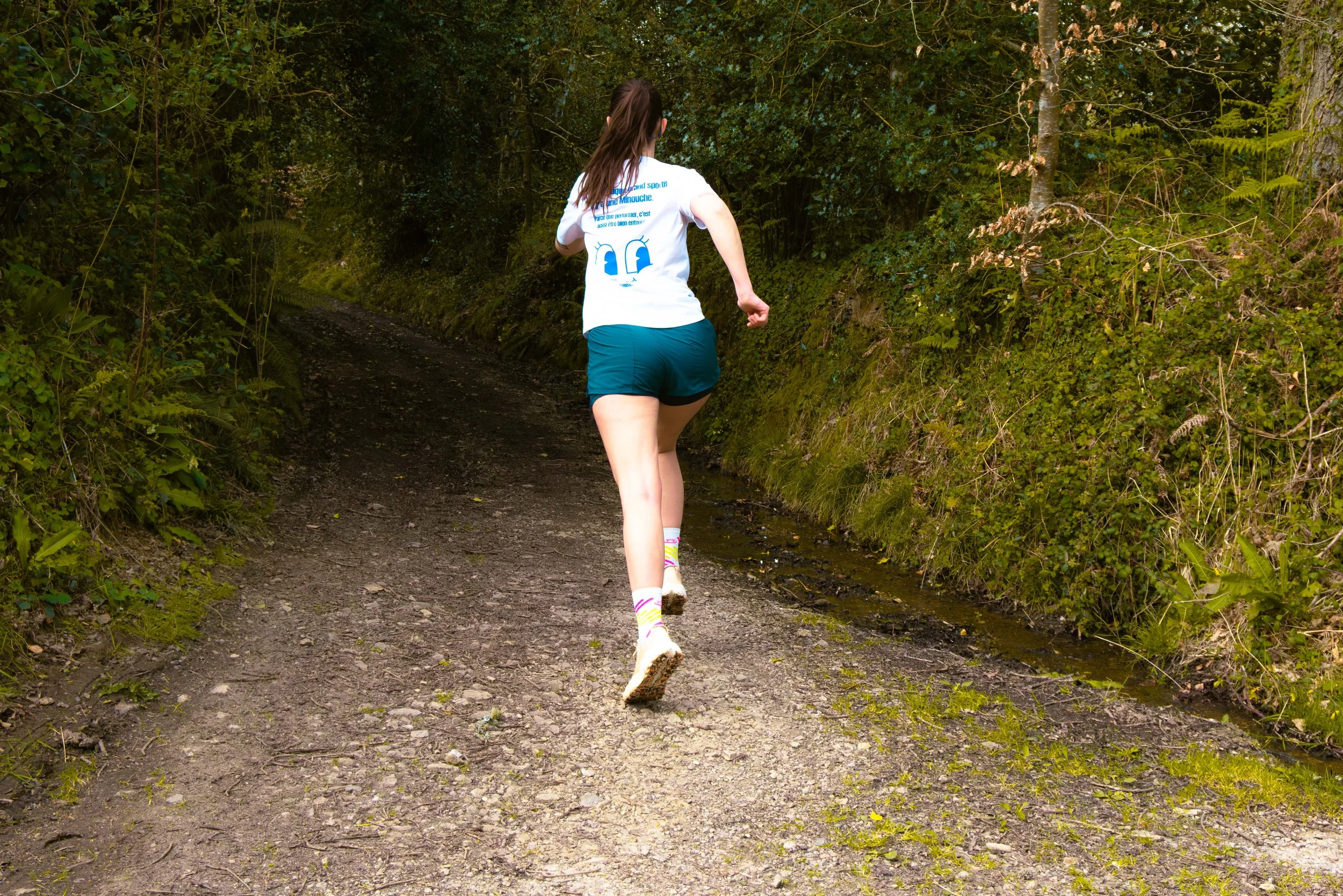 Une femme en train de courir sur un sentier forestier