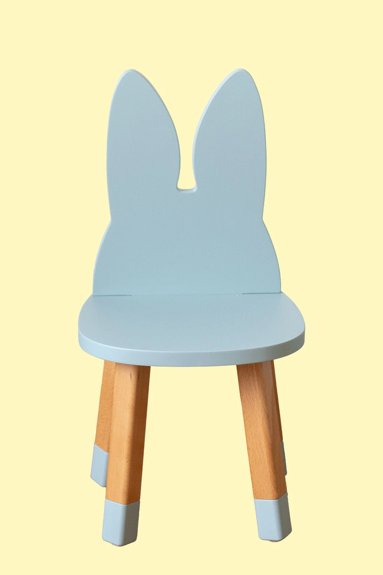 Chaise pour enfant avec dossier en forme de lapin, base en bois et pieds gris, sur fond jaune pâle.
