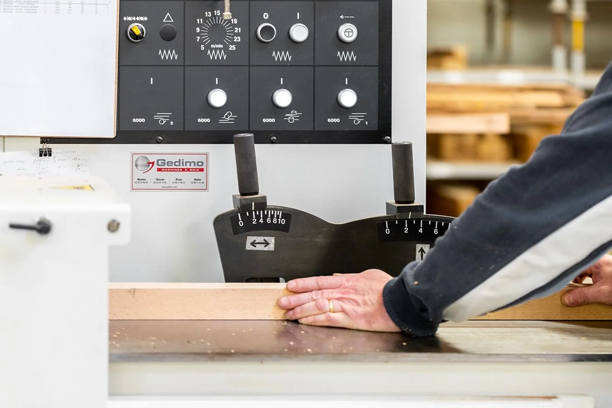 Une personne manipulant une règle de mesure sur une machine-outil dans un atelier de menuiserie.