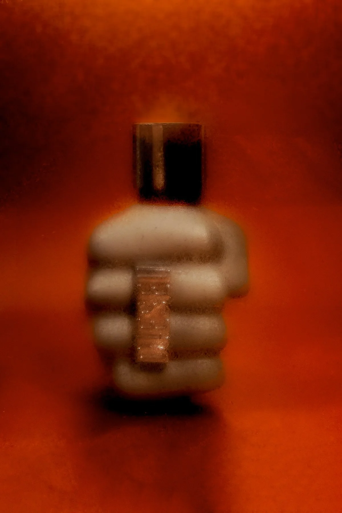 Petit objet en forme de visage humain stylisé, avec un nez en forme d'échelle, fond orange.