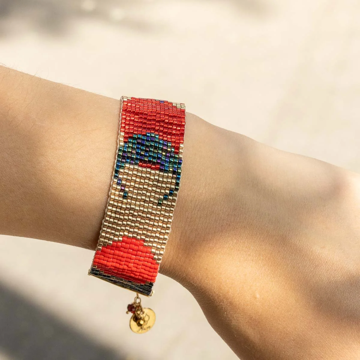 Bracelet en perles colorées avec un motif de visage et un pendentif en forme de cercle.