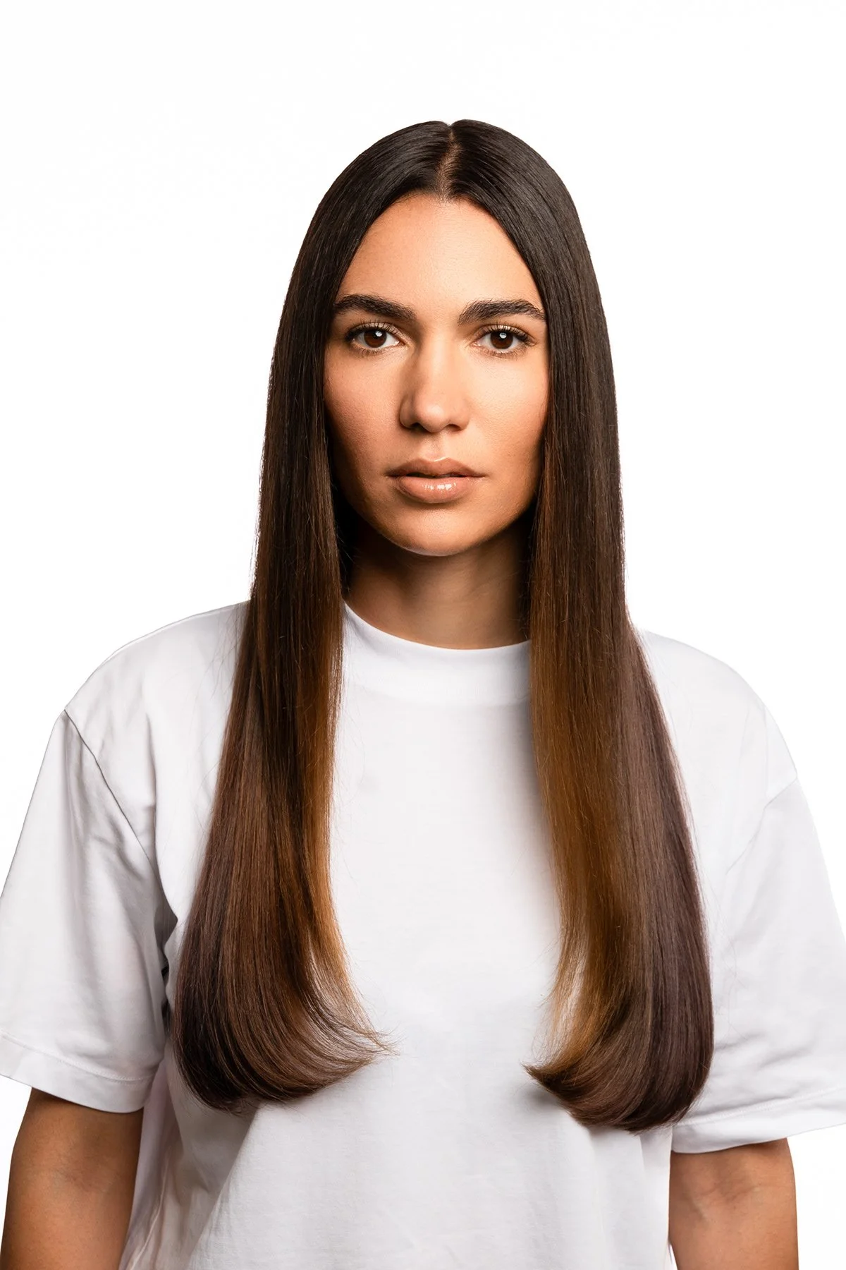 Jeune femme avec cheveux longs et lisses, portant un t-shirt blanc, regardant l'objectif.