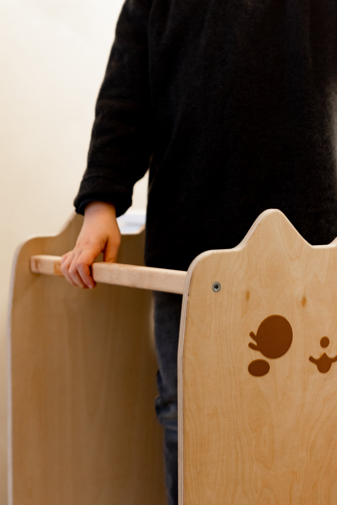 Une personne tenant une barrière en bois avec un dessin d'ours en papier sur le côté.