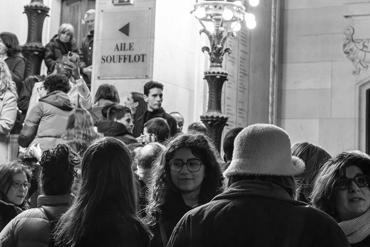 Groupe de personnes dans une rue, plusieurs discutent ou prennent des photos, ambiance nocturne