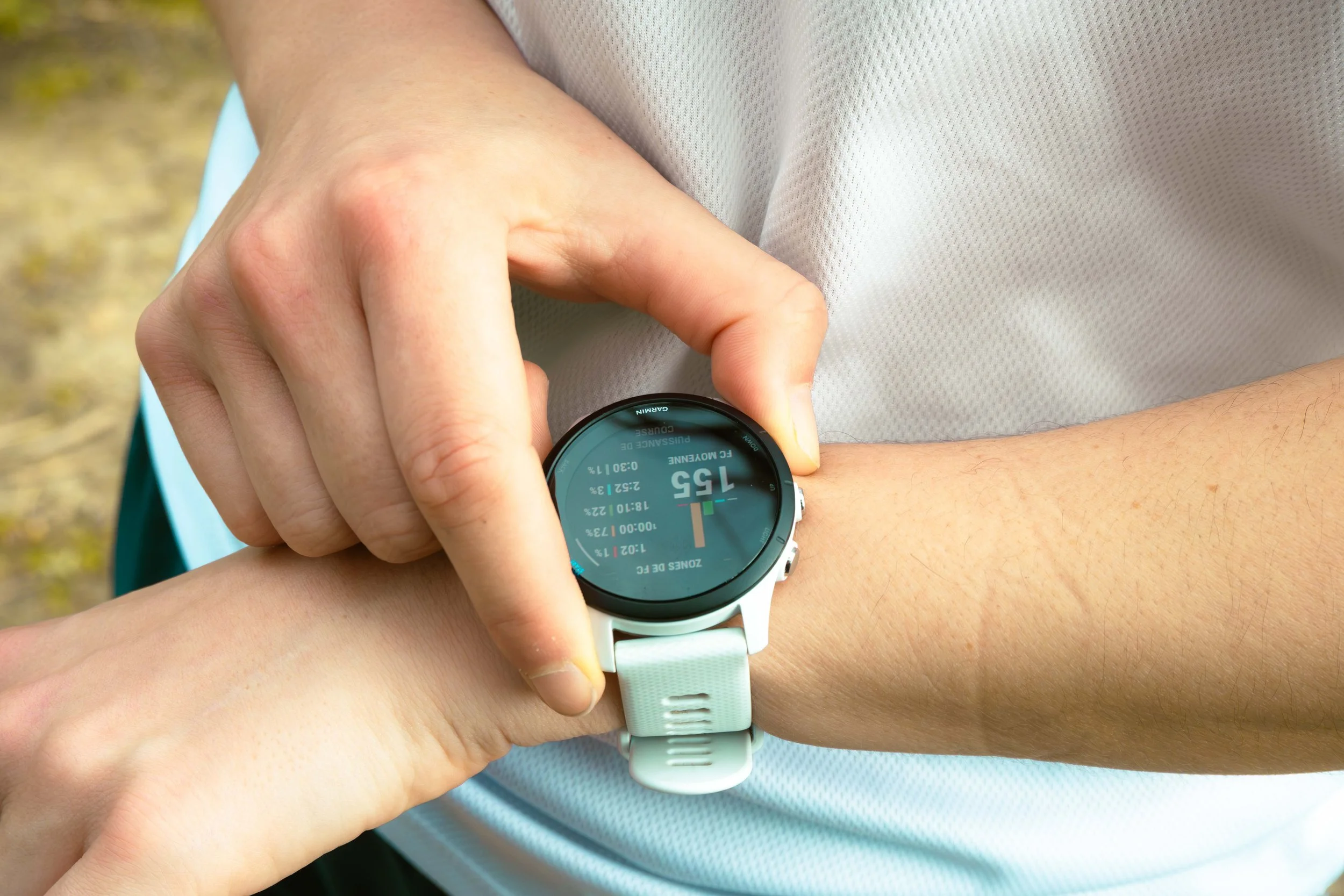 Une personne regarde une montre connectée en extérieur, vérifiant ses statistiques de course, notamment la distance parcourue de 15,5 kilomètres.