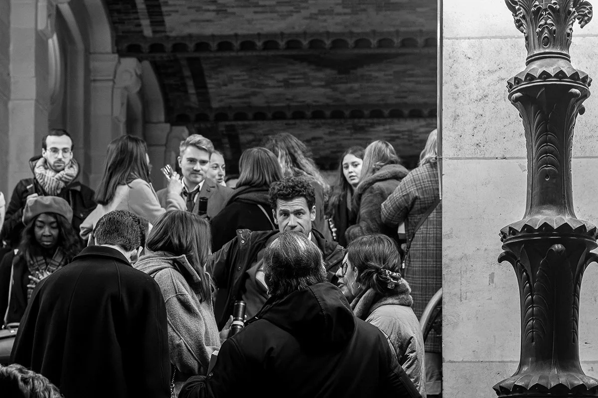 Groupe de personnes dans un lieu intérieur, discutant et socialisant, avec une colonne architecturale visible sur le côté droit.