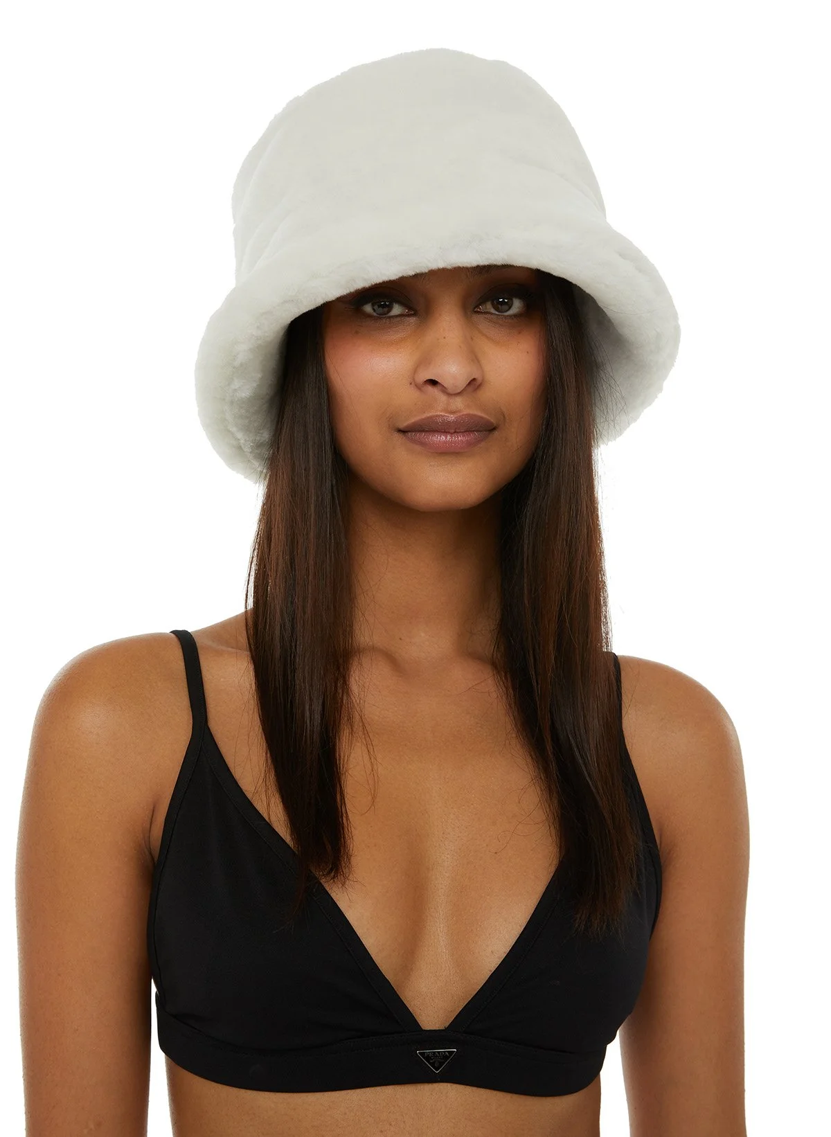 Une femme portant un chapeau blanc en fourrure et un haut noir à bretelles, fond blanc.