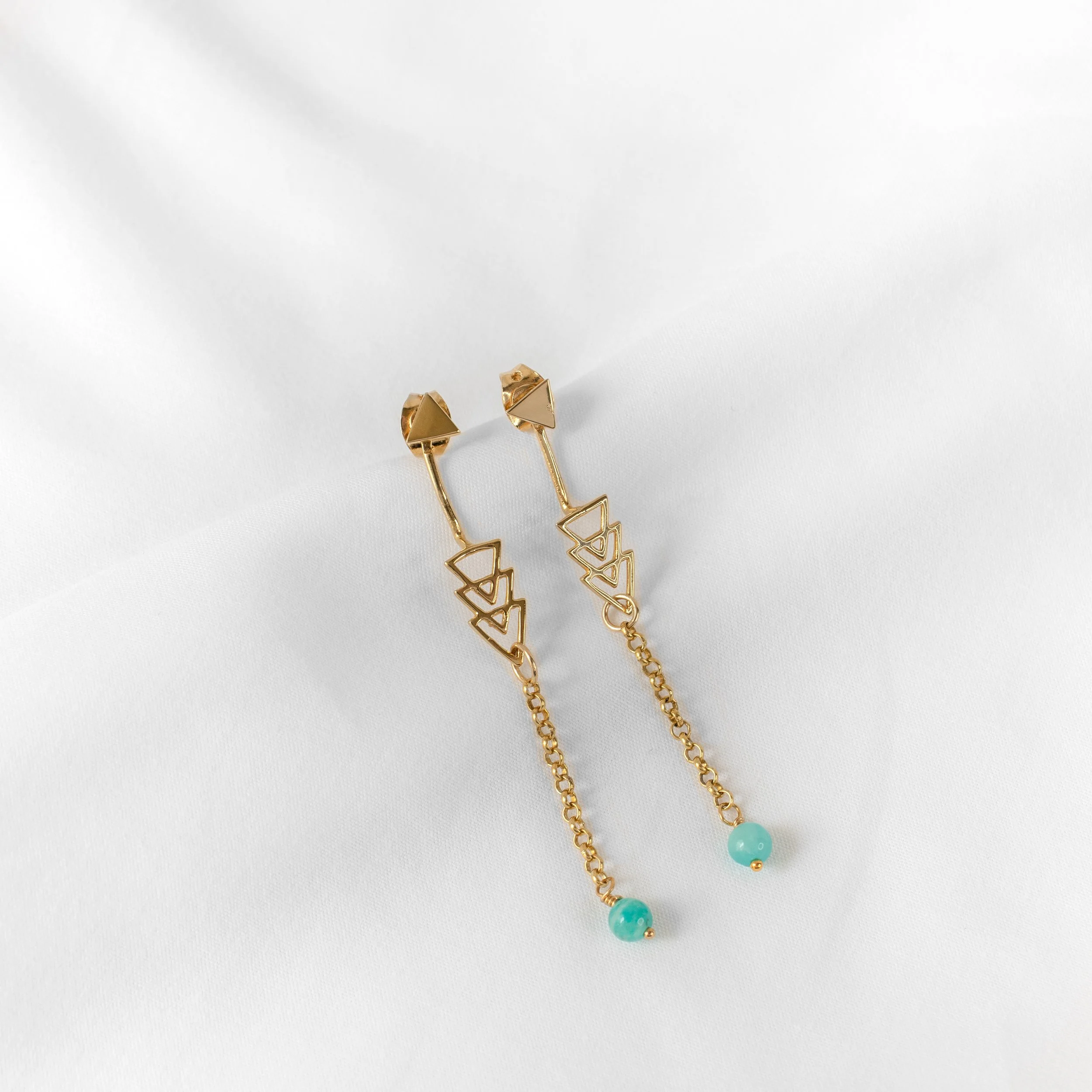 Boucles d'oreilles en or avec des pendentifs en forme de triangles et de petites perles bleues suspendues.