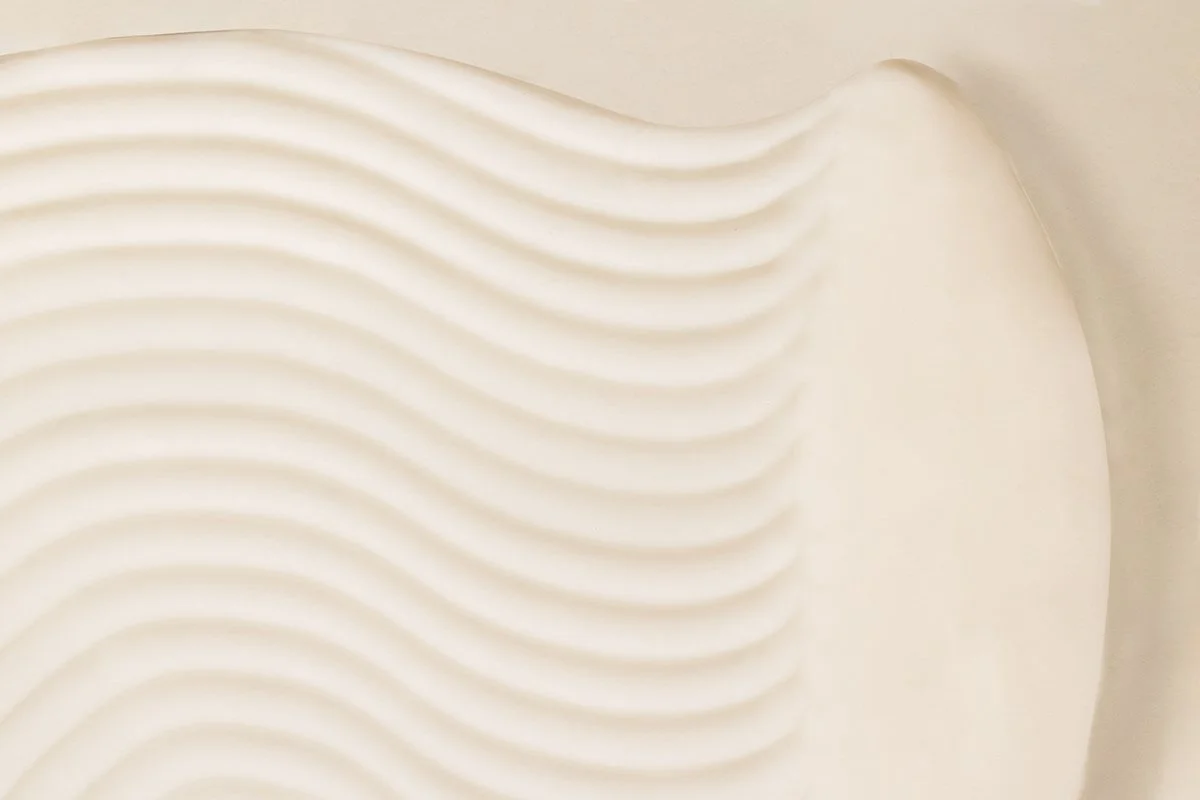 Détail d'une surface avec des lignes ondulées en relief, de couleur blanche ou crème.