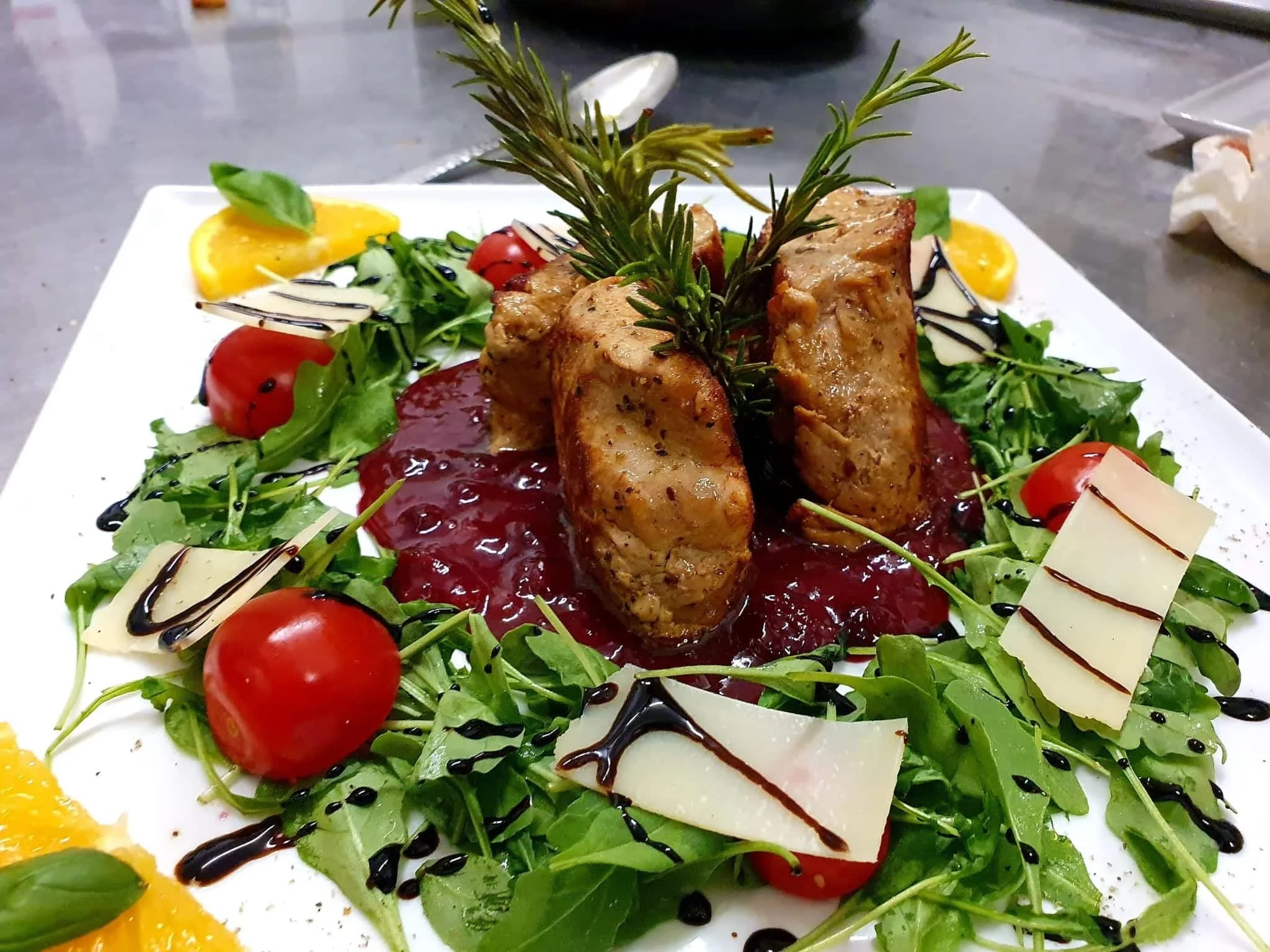 Bunter gemischter Salat mit Tomaten, Paprika, Käsescheiben, Gurken, Rinderschnitzel, Balsamico- und Schokoladensauce auf weißem Teller.