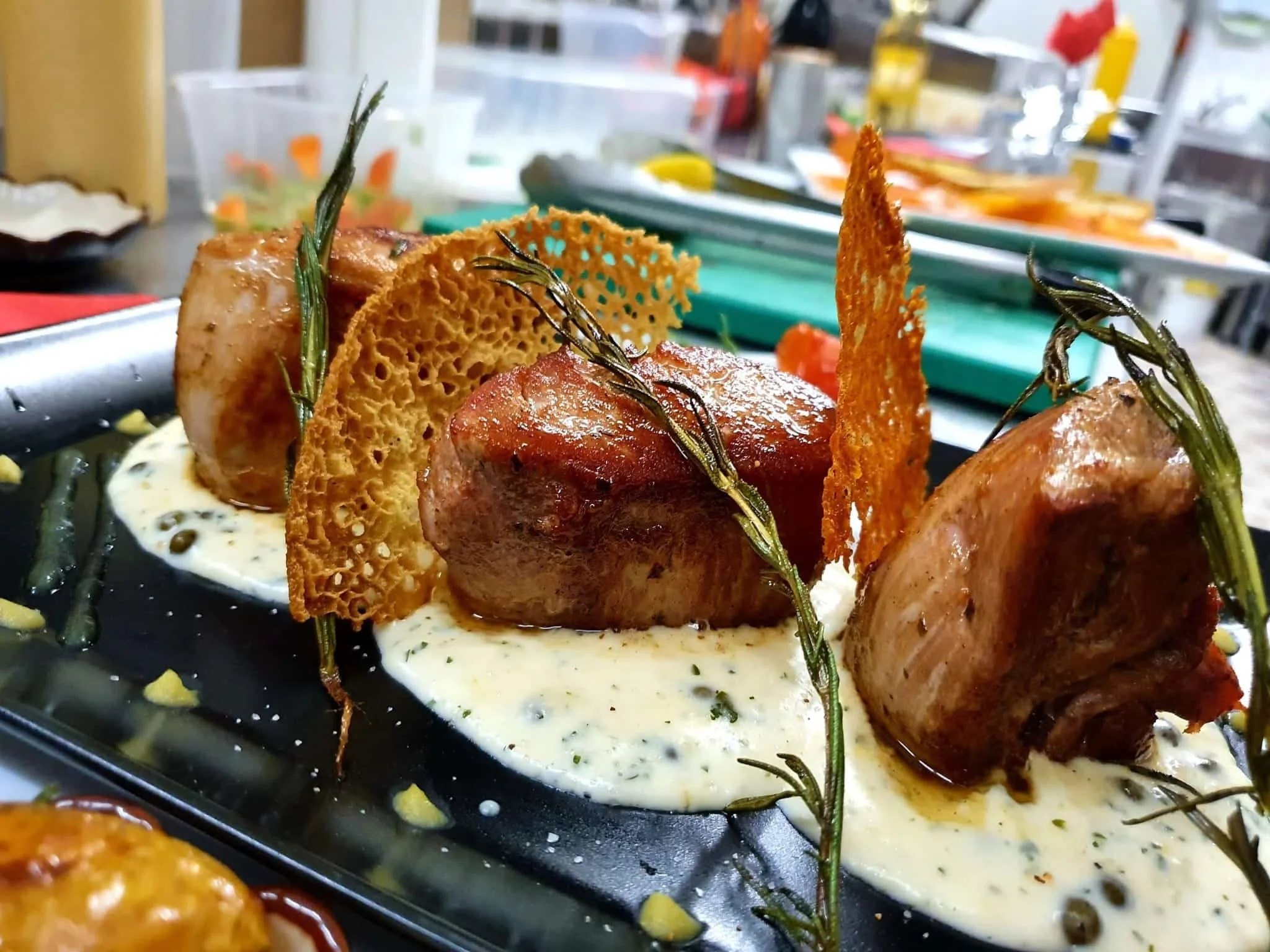 Gourmetgericht mit gerolltem Fleisch, knusprigem Tuch und Kräutern auf Soße