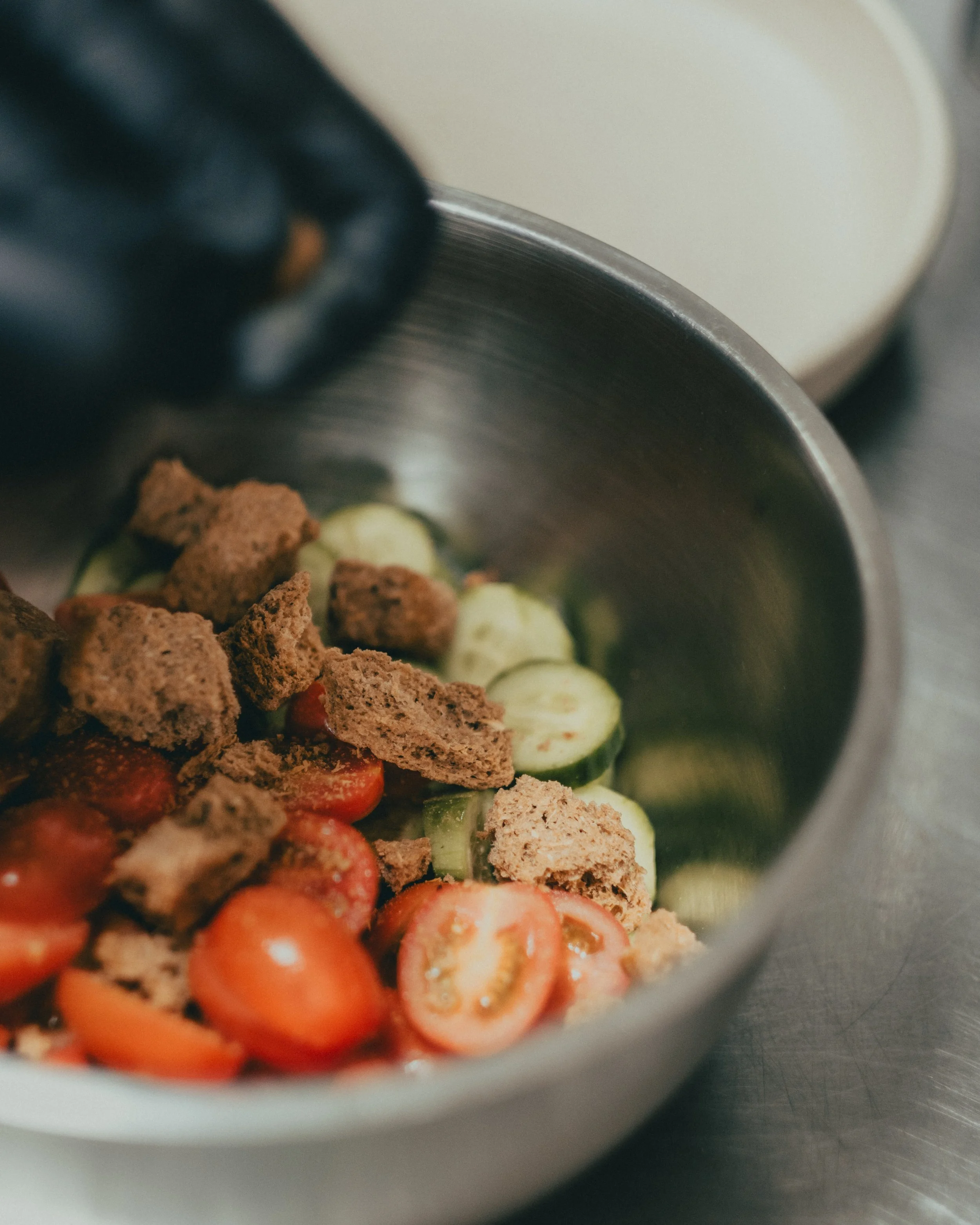 Close-up of chopped vegetables and crumbled ground meat in a metal mixing bowl
