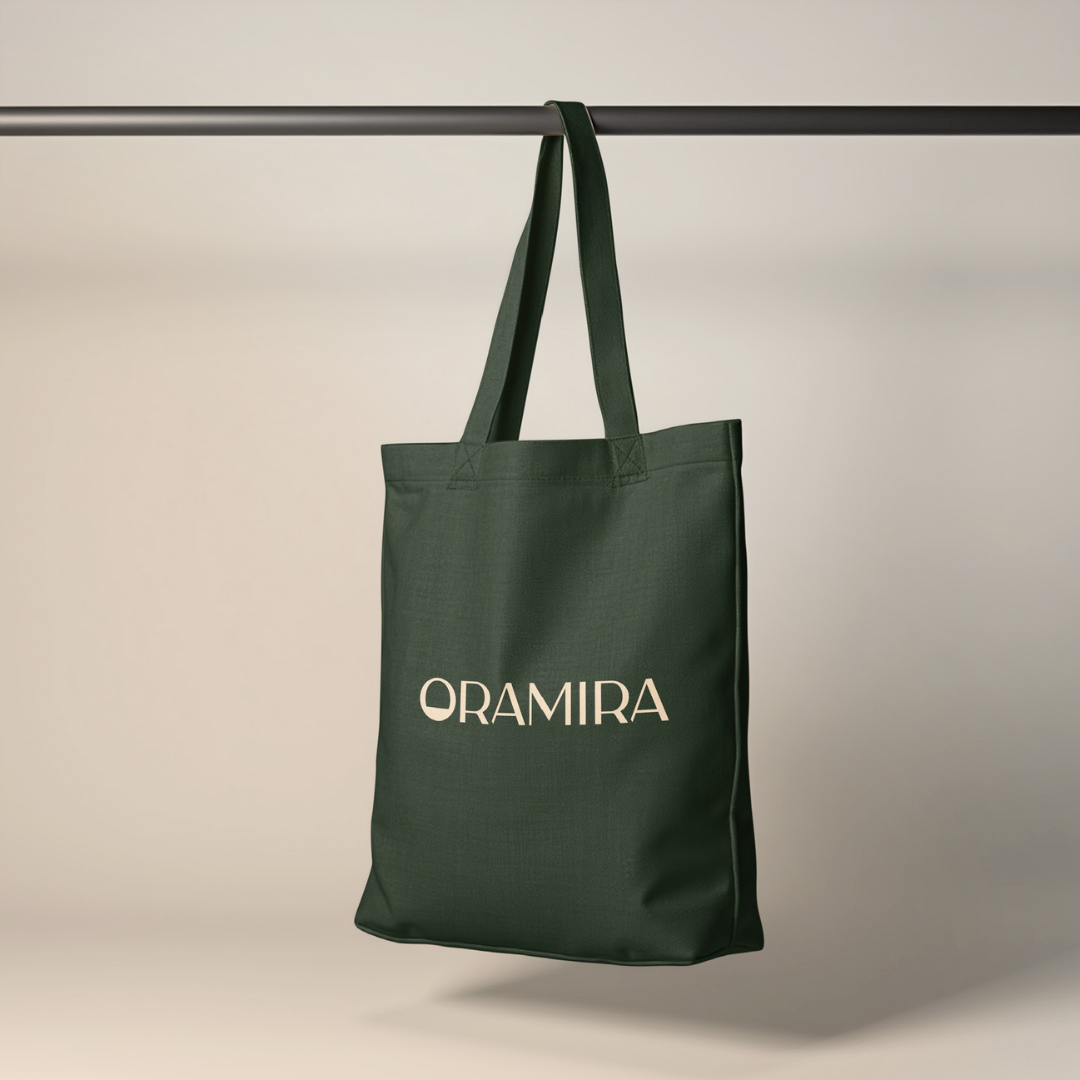 A dark green tote bag hanging from a black horizontal bar with the word 'ORAMIRA' printed in white on the front.