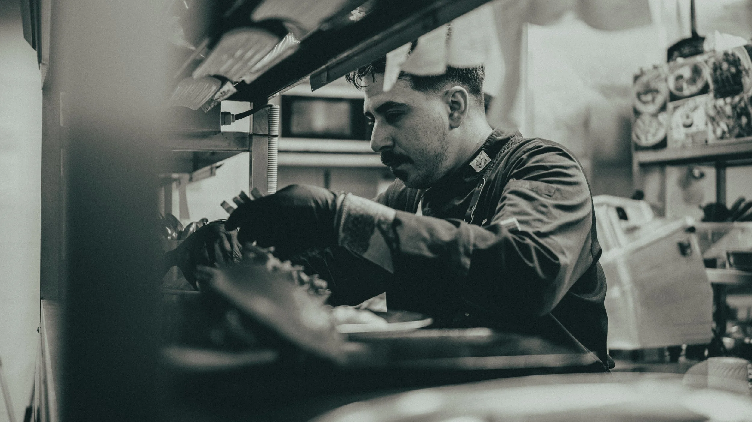 A man in a uniform working on a mechanical device in a workshop or garage.