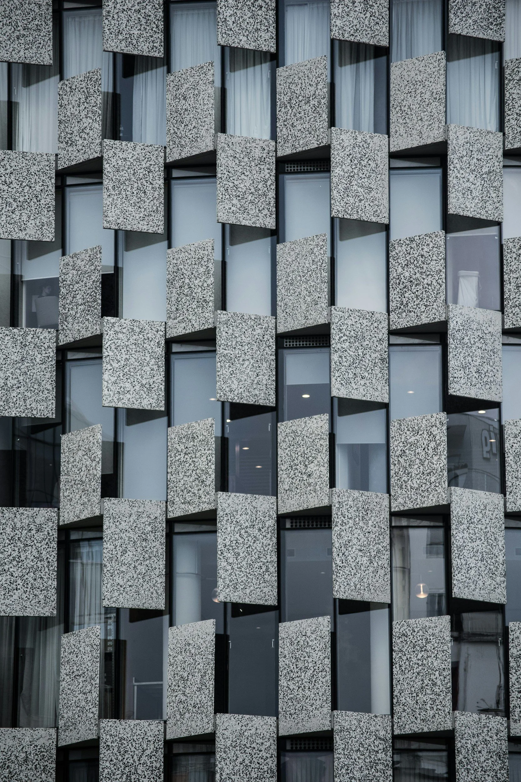 Close-up of a modern building facade with a pattern of textured panels and windows.