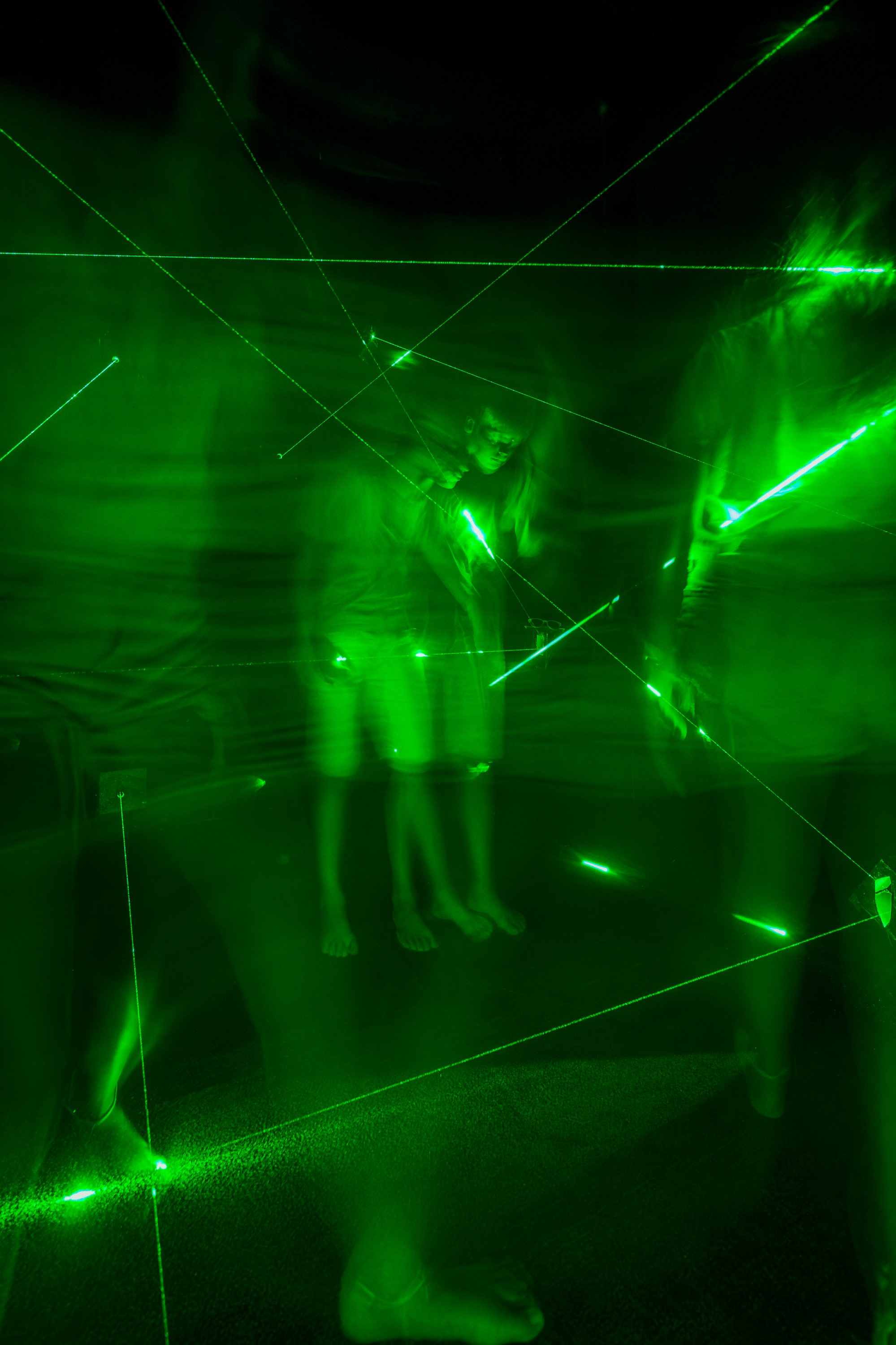 People standing in a room illuminated by green laser lights creating a star-like pattern.