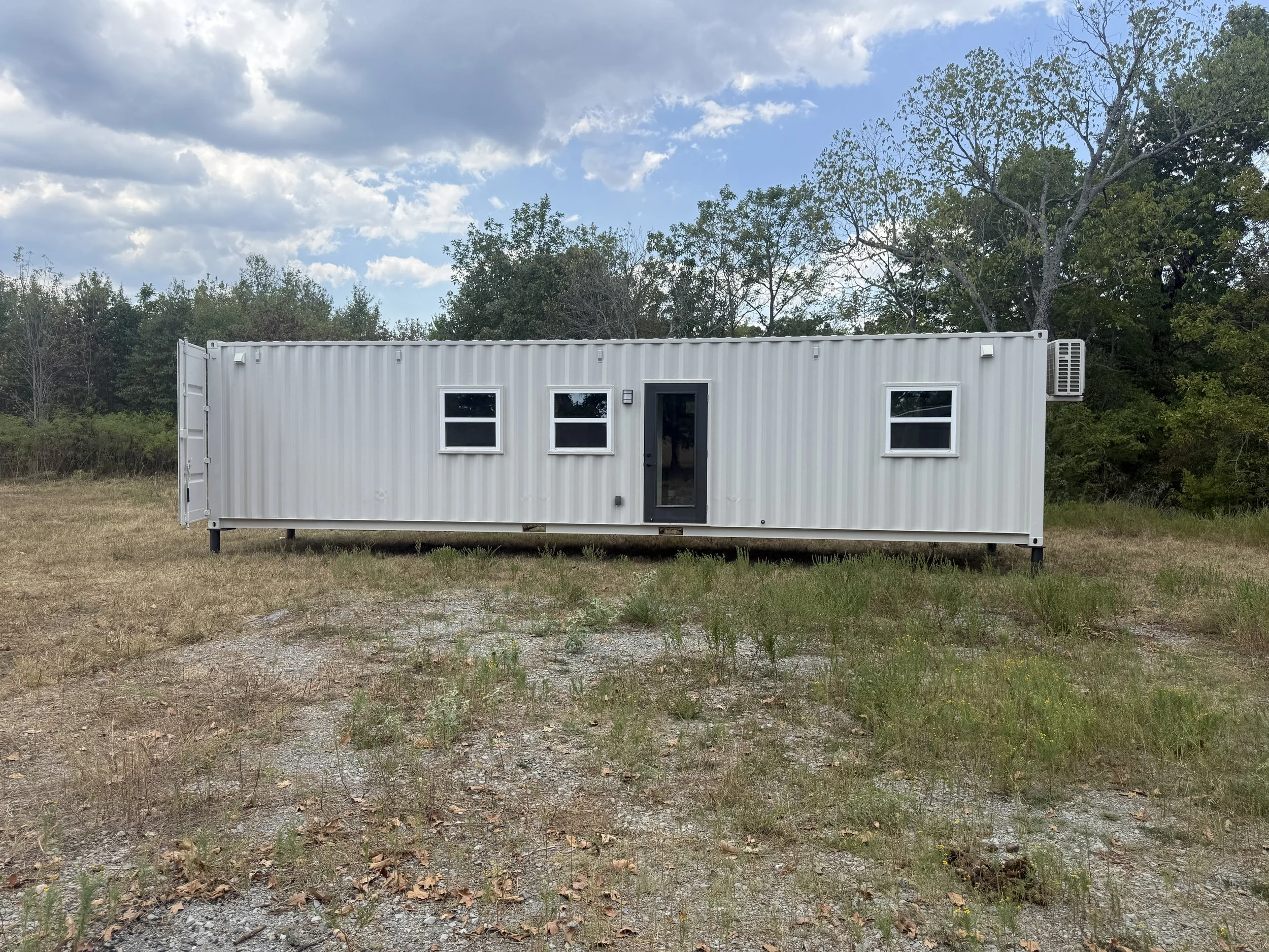 Shipping container home installed on concrete piers, elevated and leveled above the ground with the steel container frame securely supported.