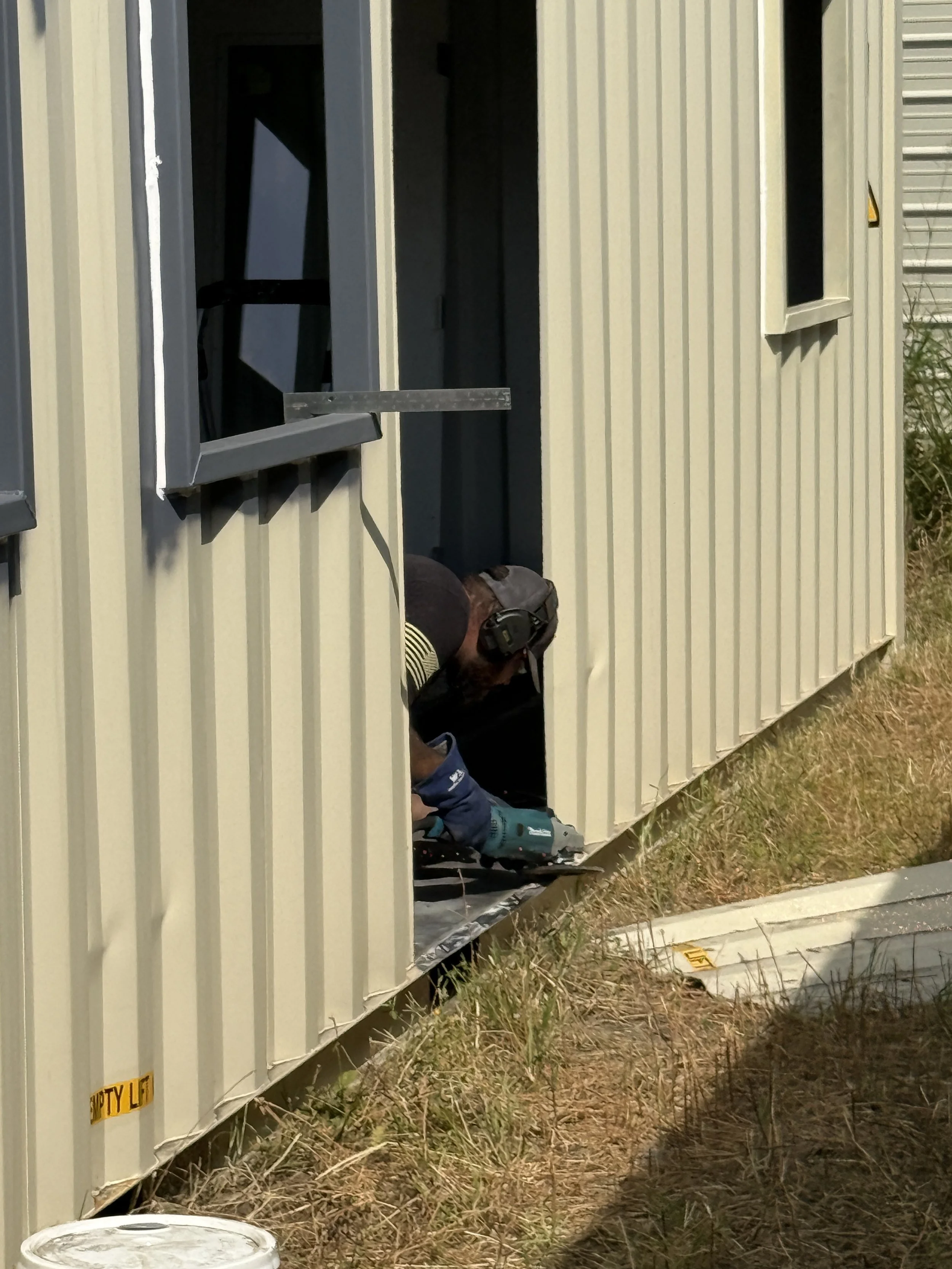 Worker grinding and preparing the door opening during construction of our 40’ high-cube shipping container home in Paris, Texas – real build process for our $65,000 fully finished turnkey model