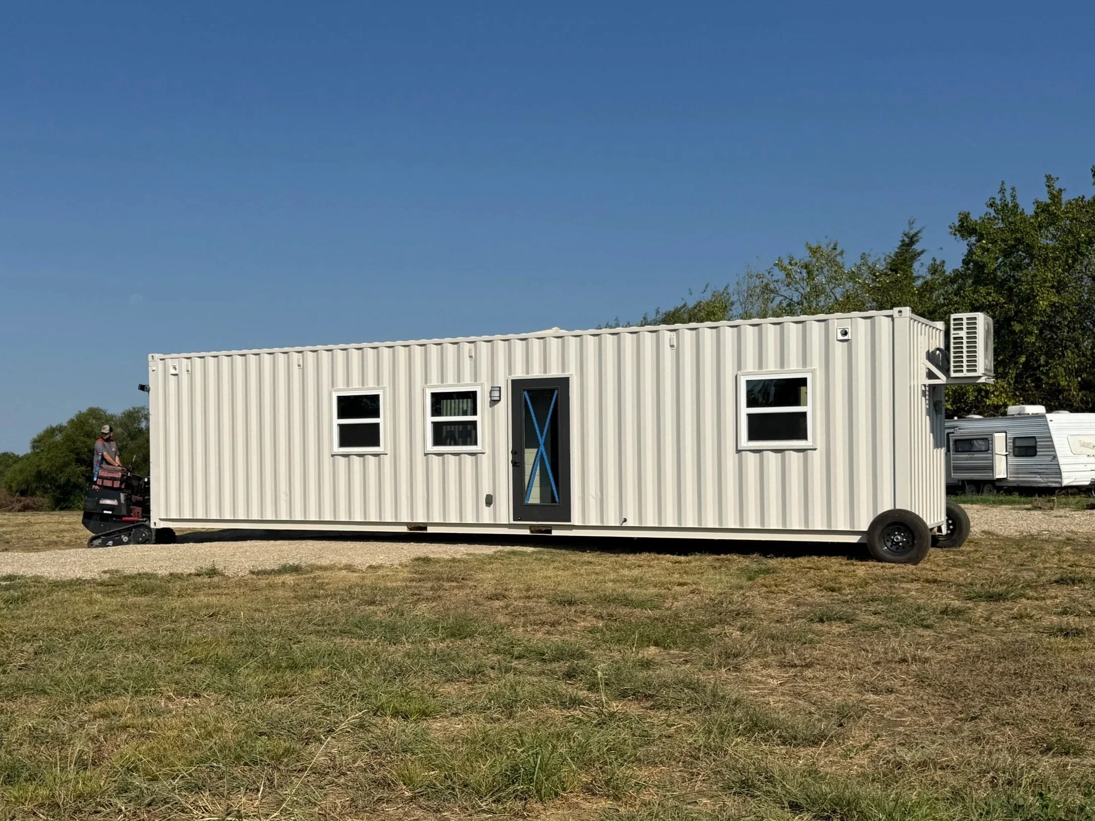 Shipping container home being moved with a container mule and dolly wheels for positioning and transport.