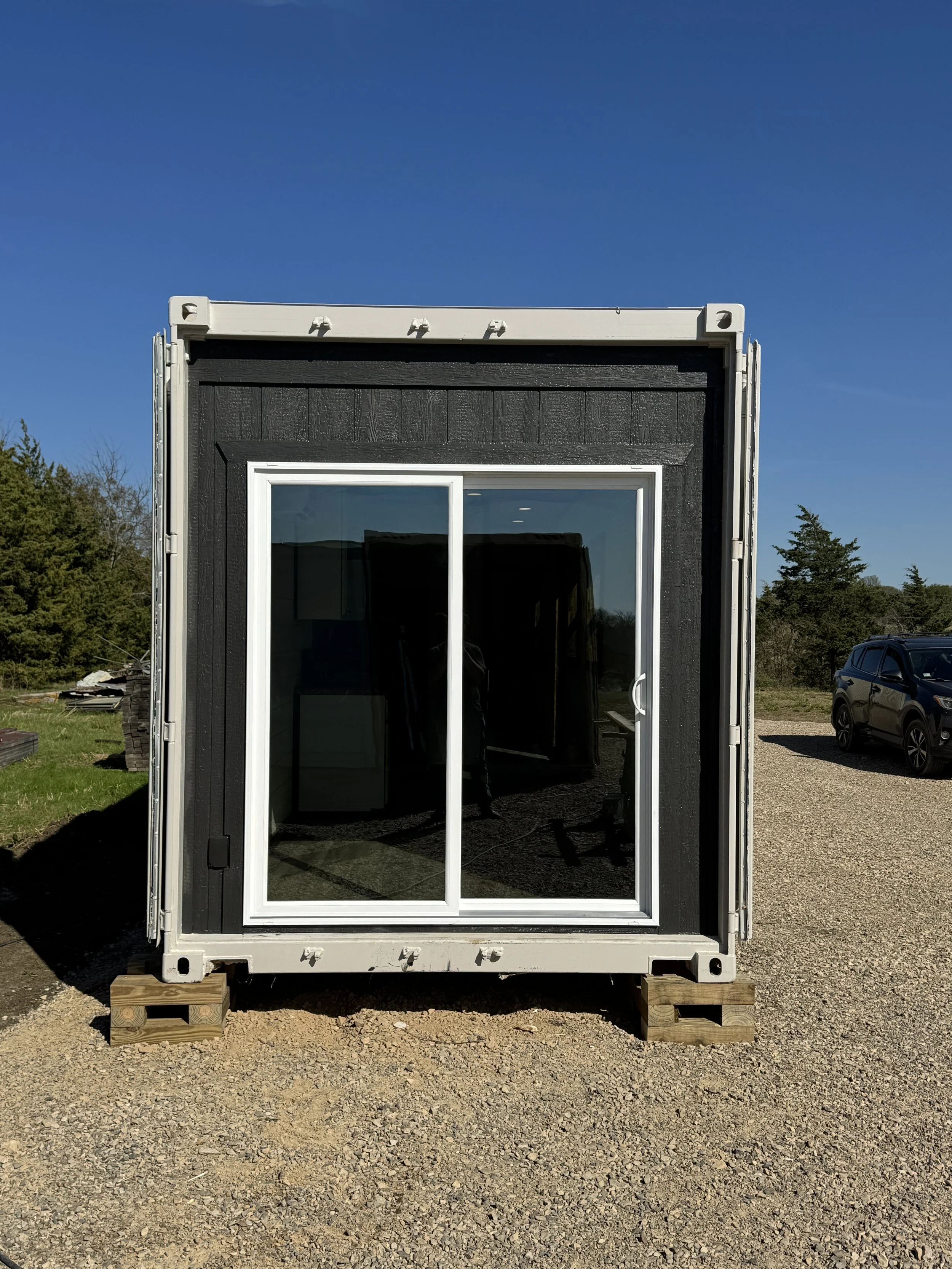 Exterior view of our completed 40’ high-cube shipping container home with large sliding glass door in Paris, Texas – part of our $65,000 fully finished turnkey model