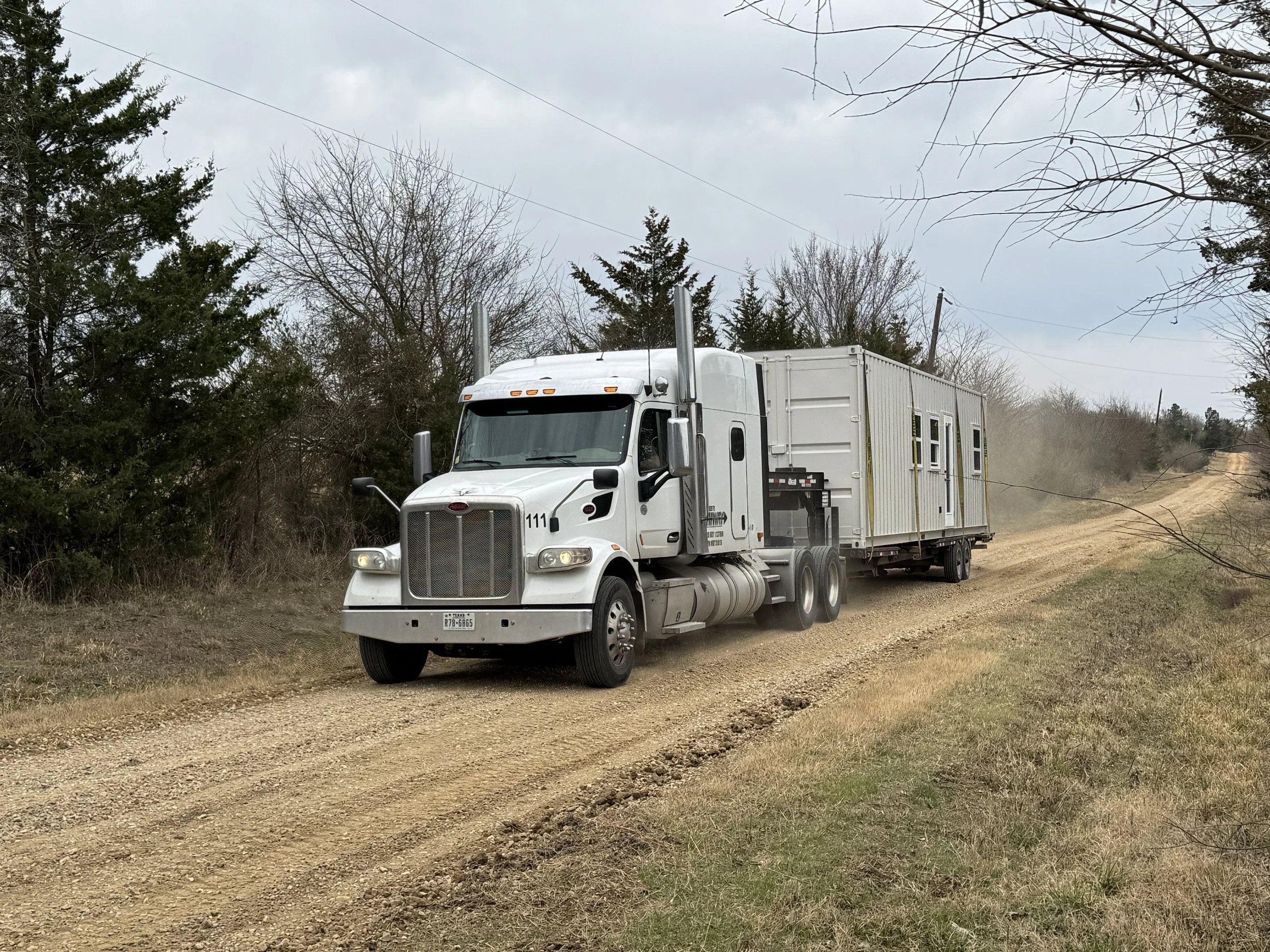 Semi-truck delivering a 40’ shipping container home in Texas – we provide free professional delivery and placement within 100 miles of Paris, Texas as part of our $65,000 turnkey model