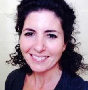 A woman with curly dark hair smiling at the camera.