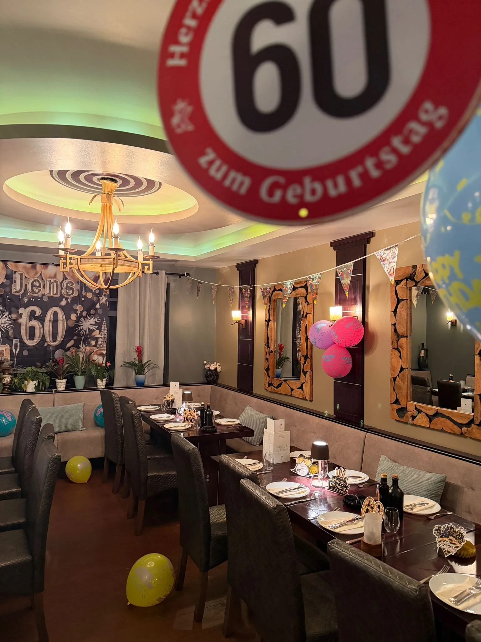 Ein festlich dekorierter privater Raum im Restaurant mit Tischen, Stühlen, Luftballons, Handdekorationen und einer Geburtstagstafel im Hintergrund, vermutlich für eine Geburtstagsfeier.